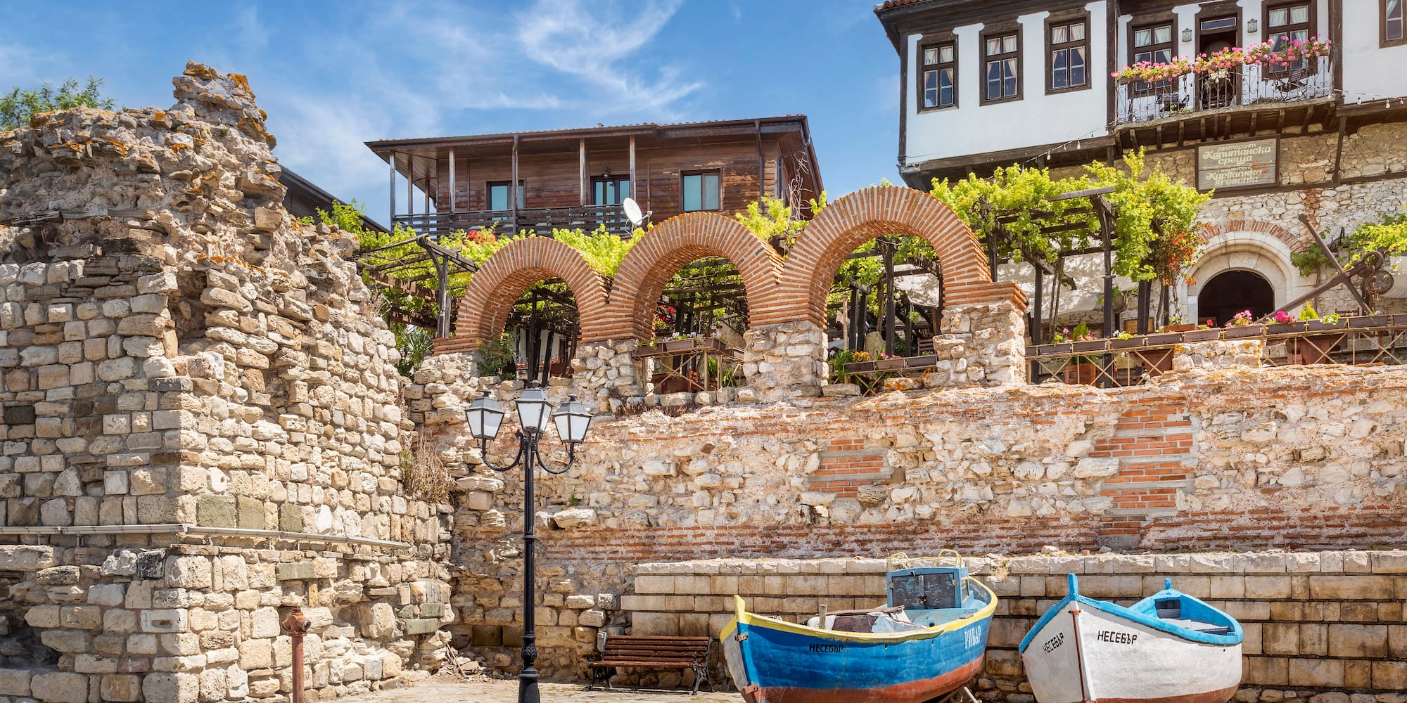 boats parked on the side of a road next to a stone wall