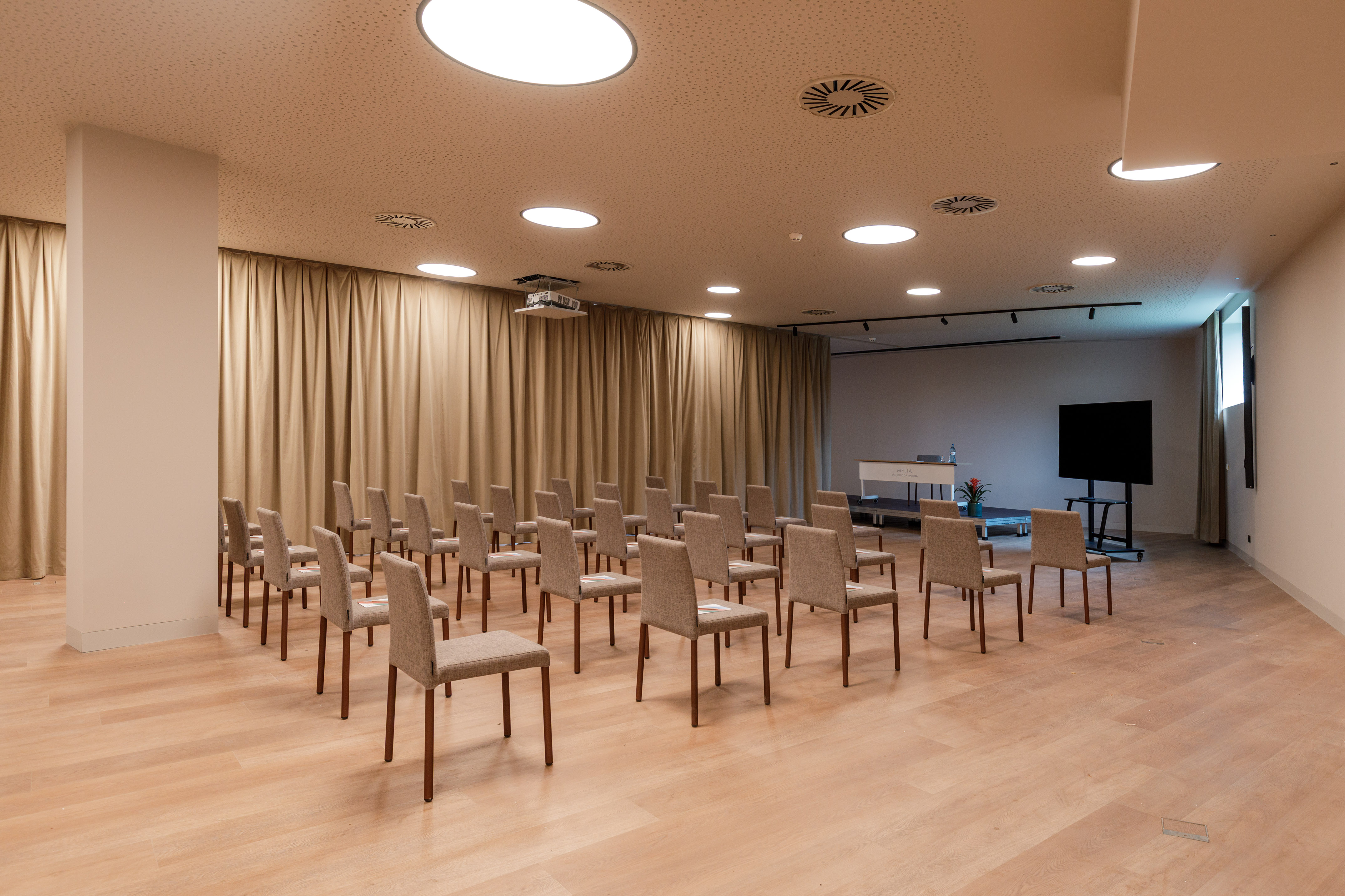 Conference room setup with chairs, projector, screen, and podium.