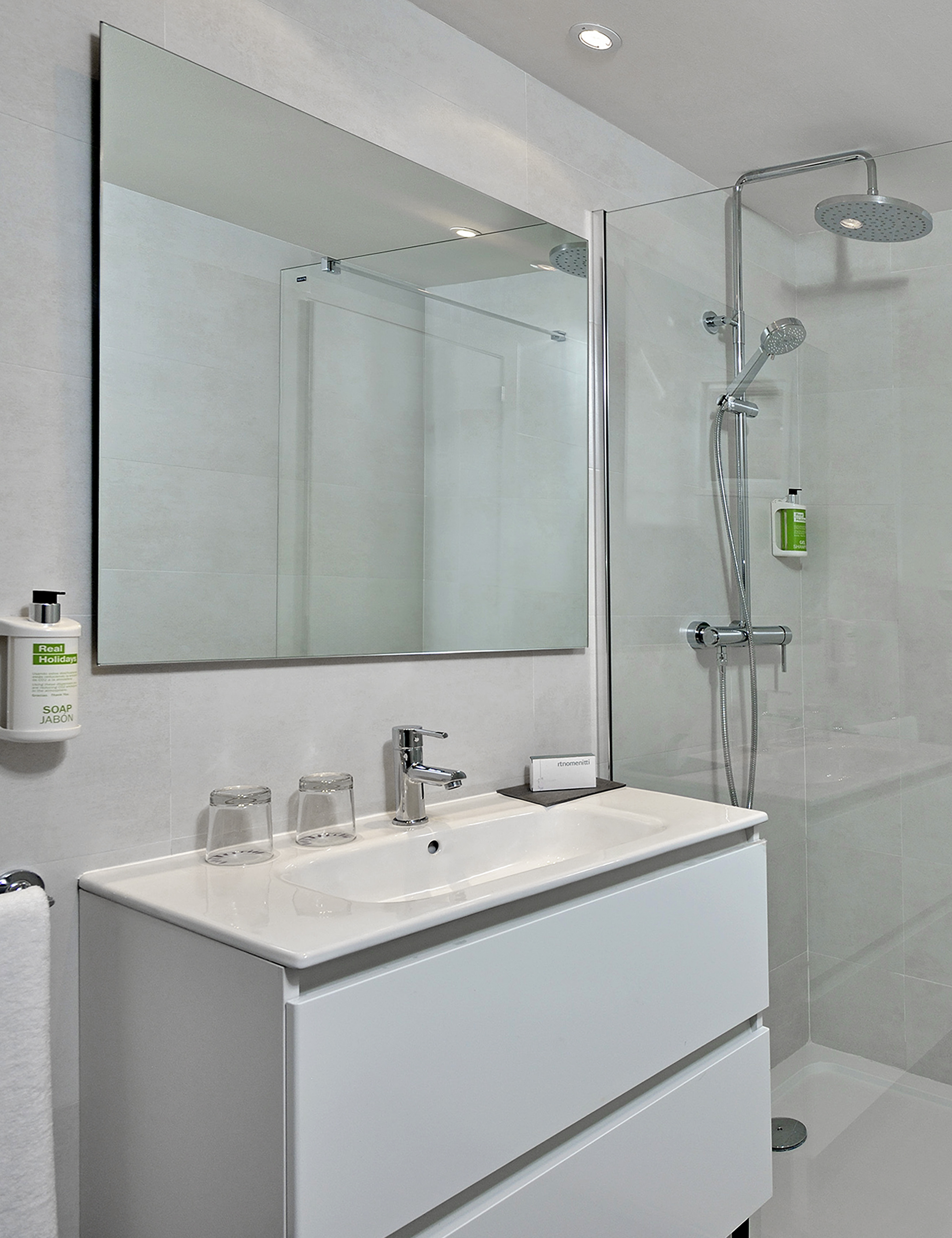 Contemporary bathroom with white vanity, large mirror, and walk-in shower.