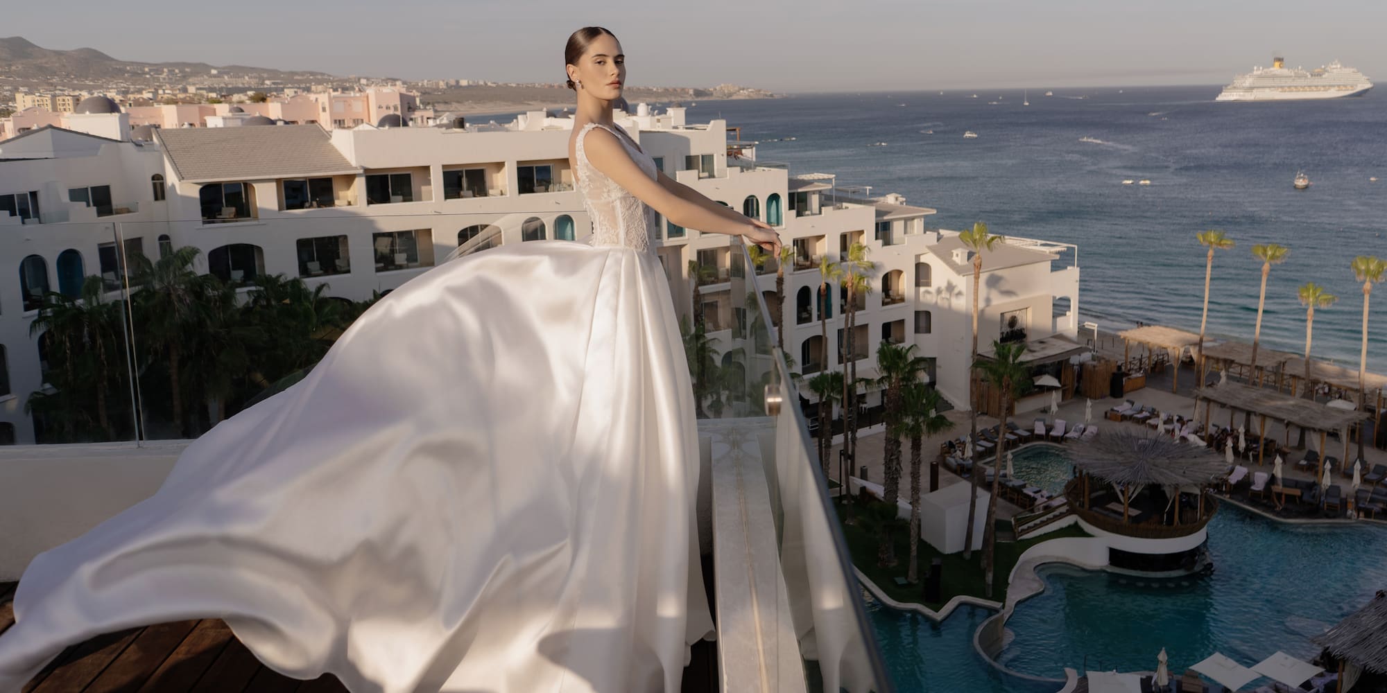 a woman in a white dress standing on a balcony overlooking a body of water