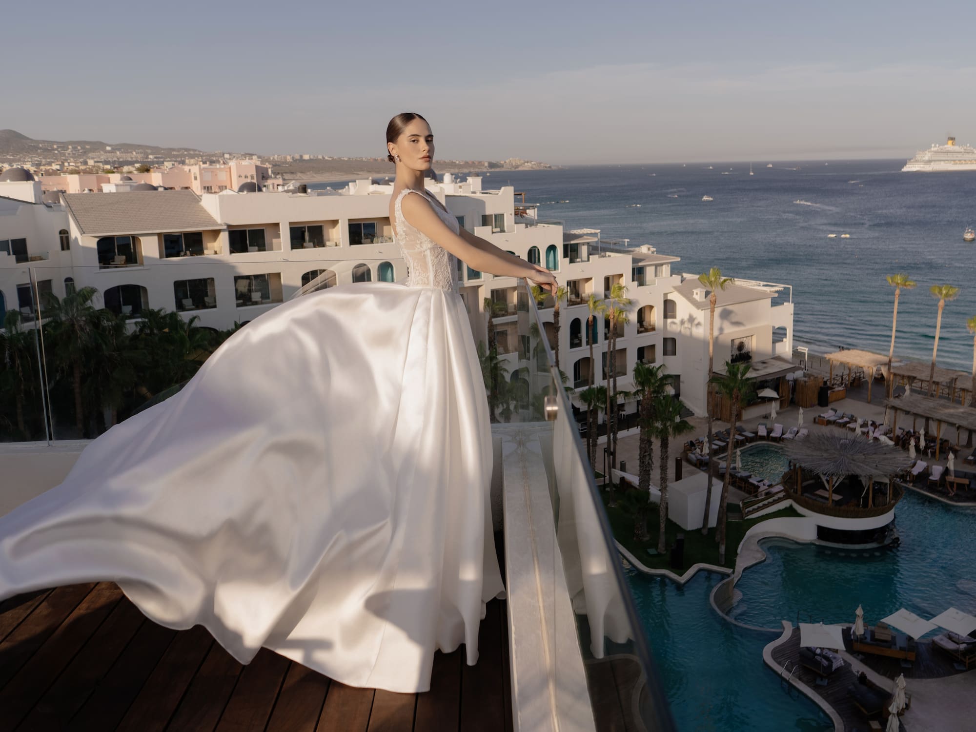 a woman in a white dress standing on a balcony overlooking a body of water