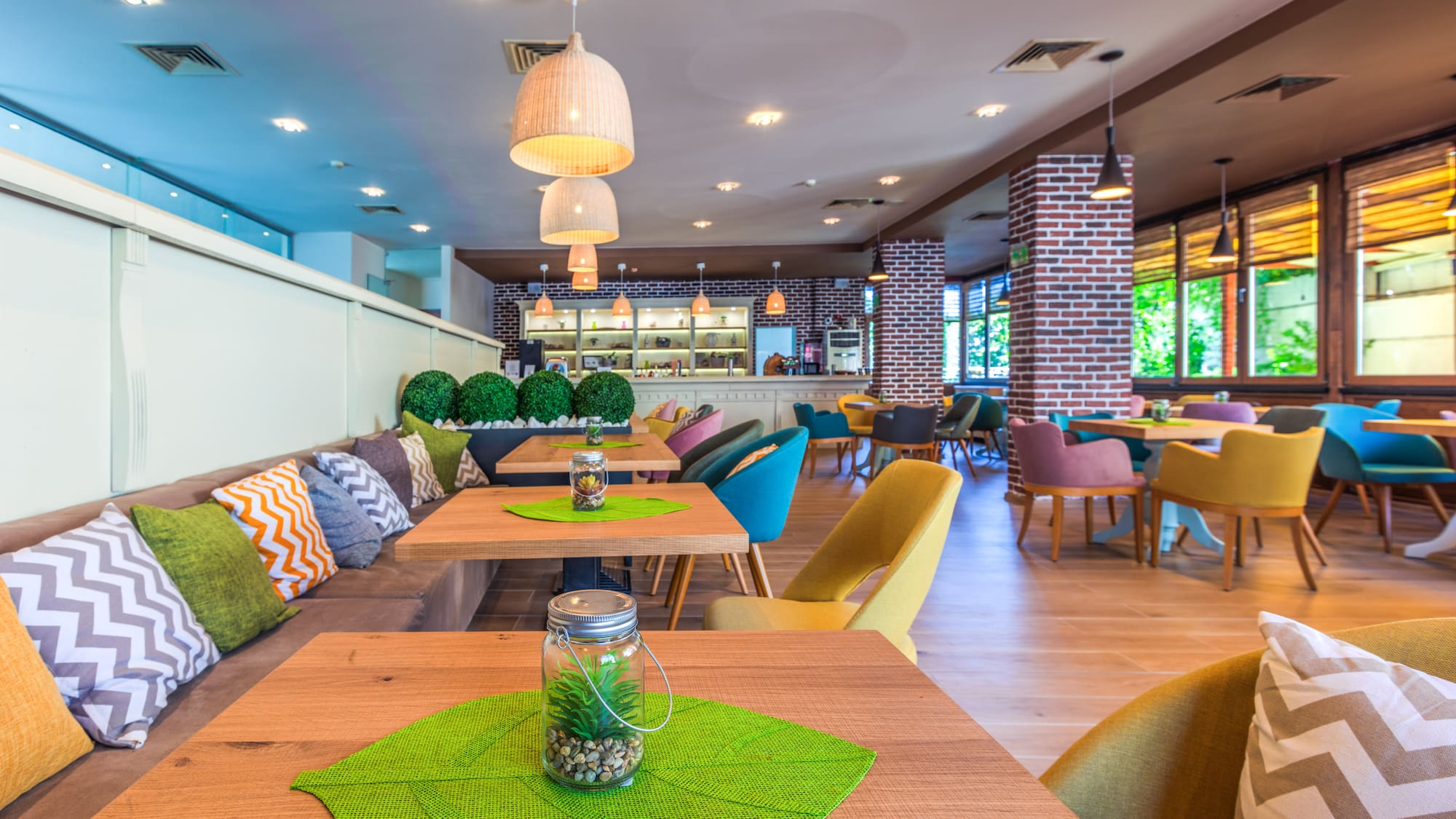 Modern cafe with colorful seating, wooden tables, and exposed brick walls.