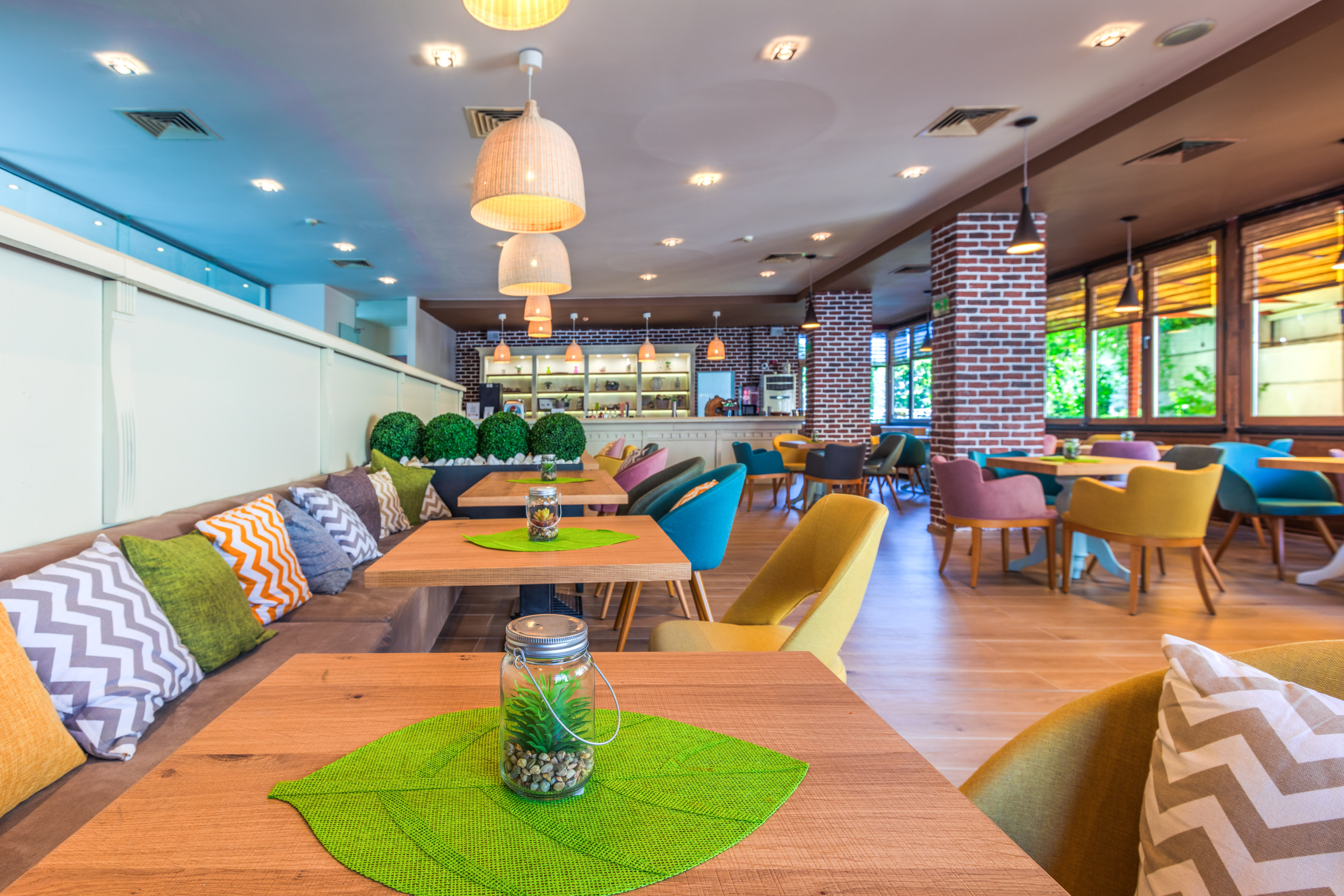 Modern cafe with colorful seating, wooden tables, and exposed brick walls.
