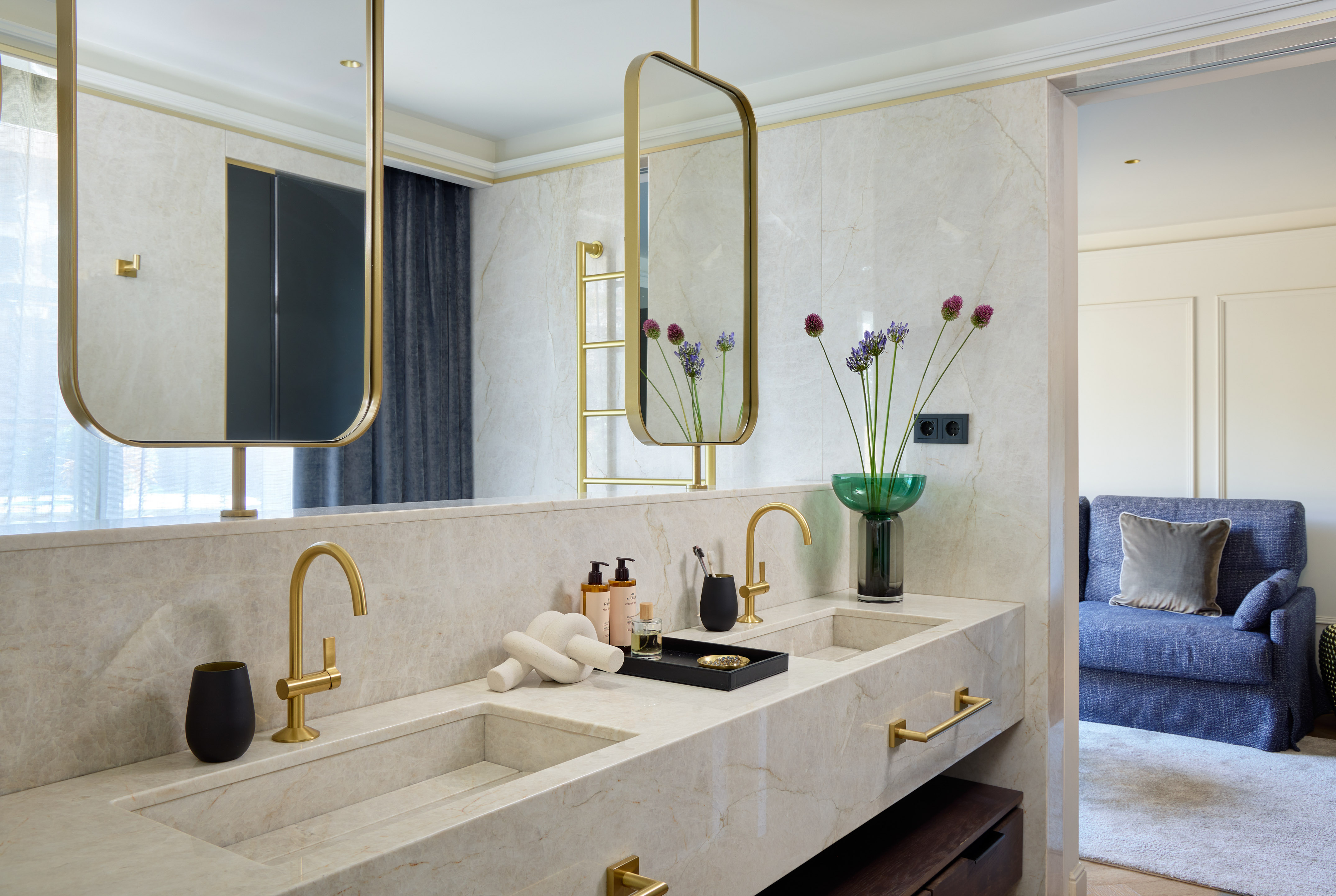 Luxury marble bathroom with gold fixtures, double vanity, and modern mirrors.