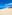 Sunny white sand beach with turquoise ocean, distant town, and palm trees.