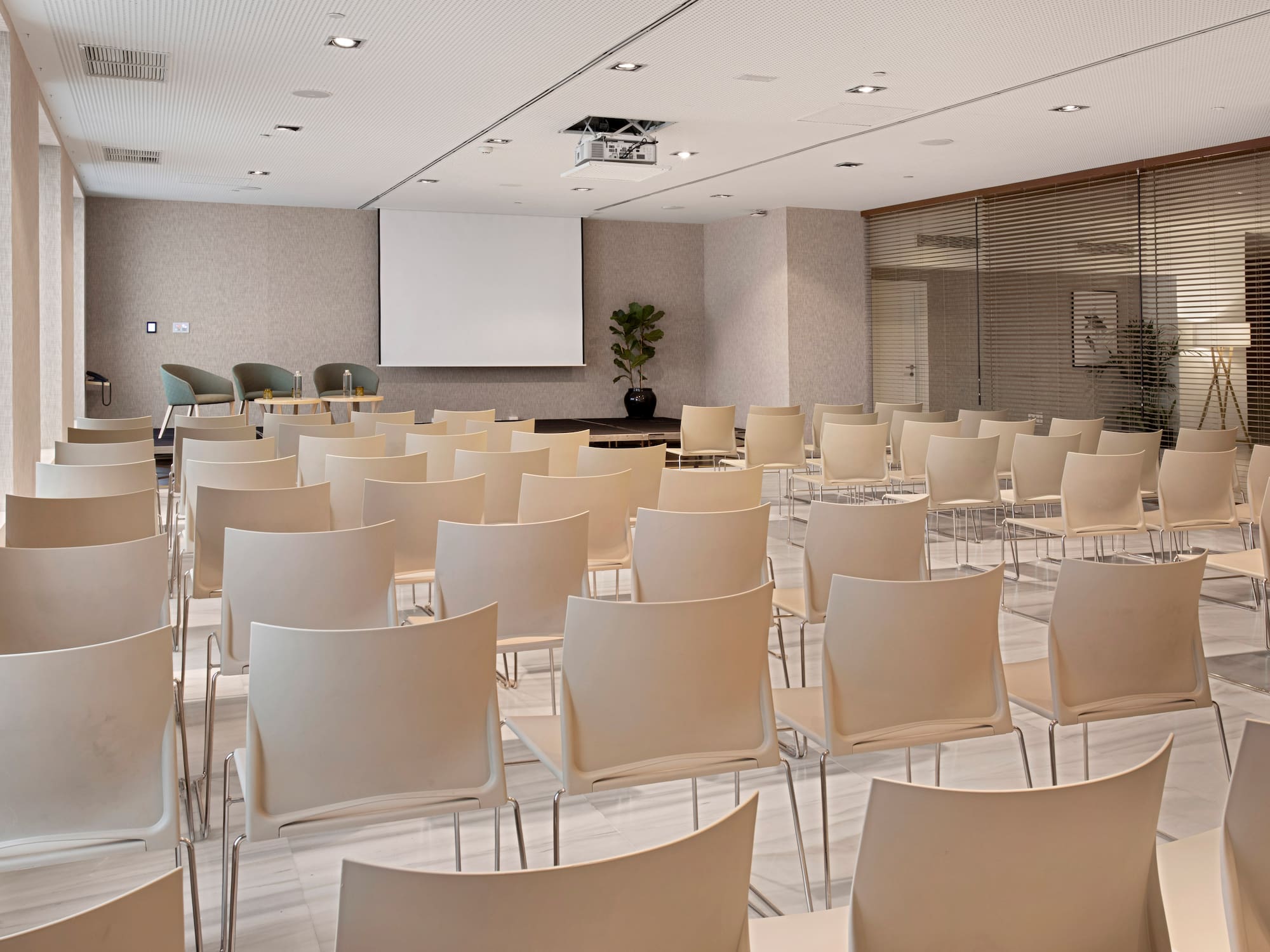 a room with white chairs and a projector screen