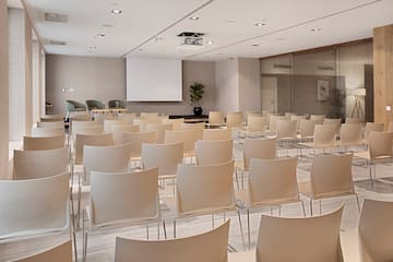 a room with white chairs and a projector screen