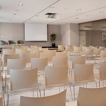 a room with white chairs and a projector screen