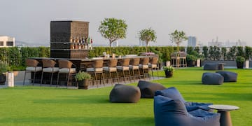 a group of chairs on a green lawn with a bar and a bench