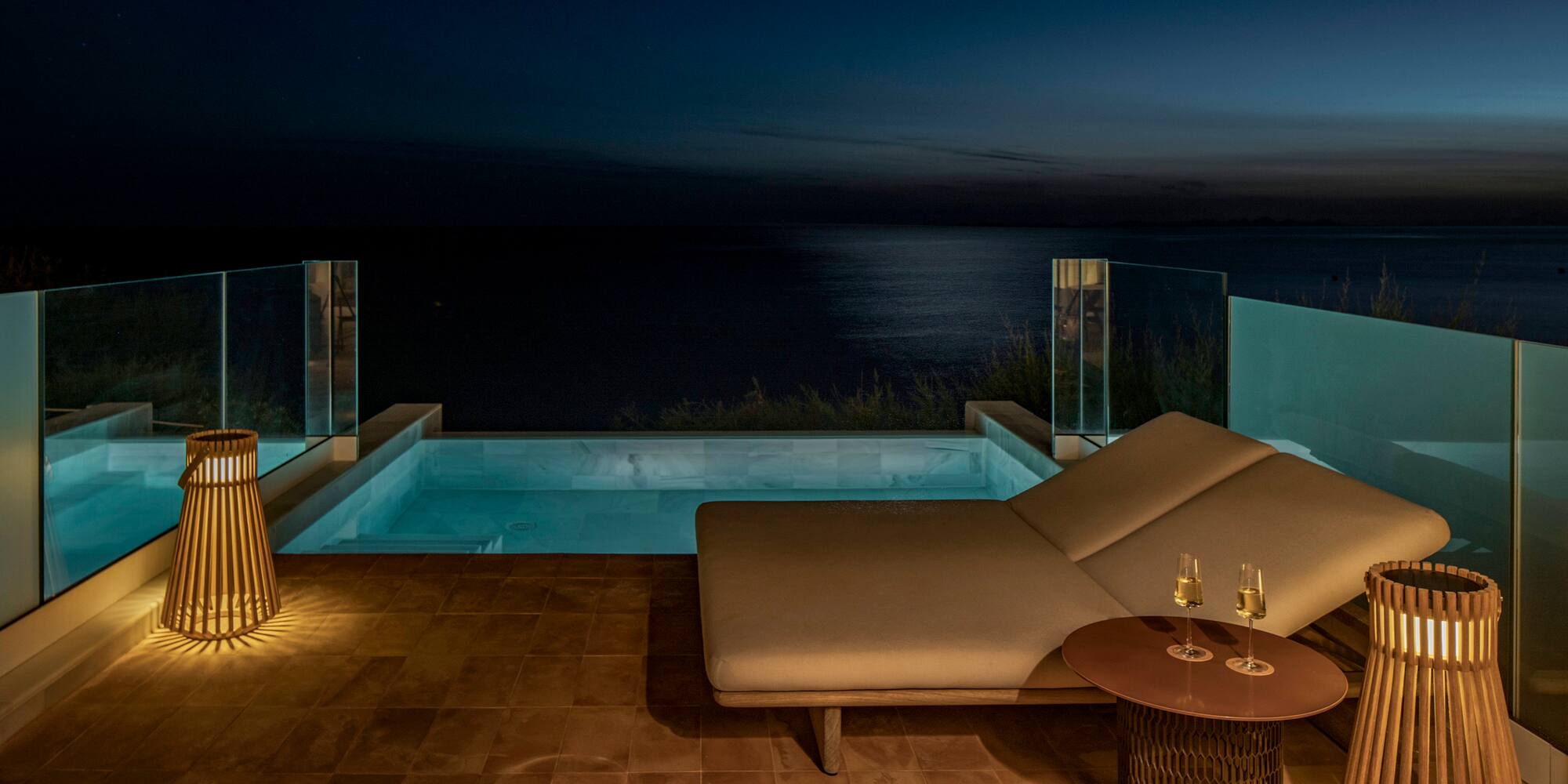 a lounge chair and a pool with a table and a lamp