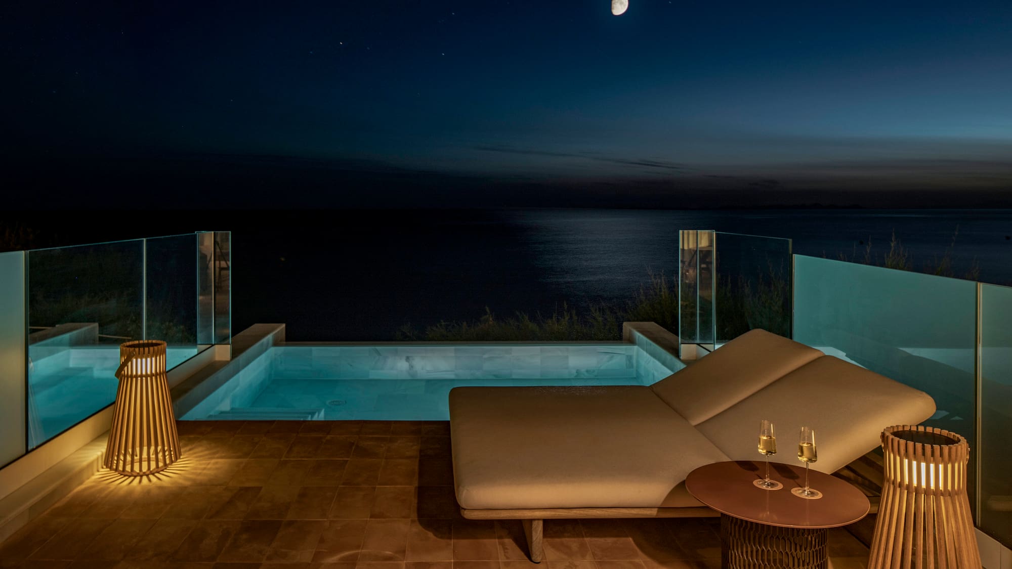 a lounge chair and a pool with a table and a lamp