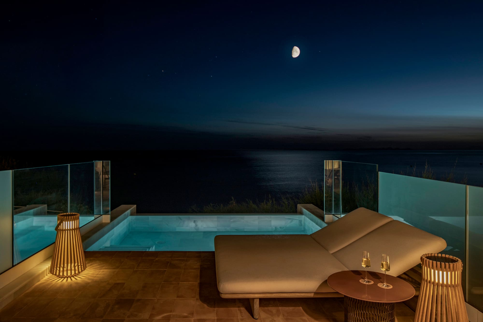 a lounge chair and a pool with a table and a lamp