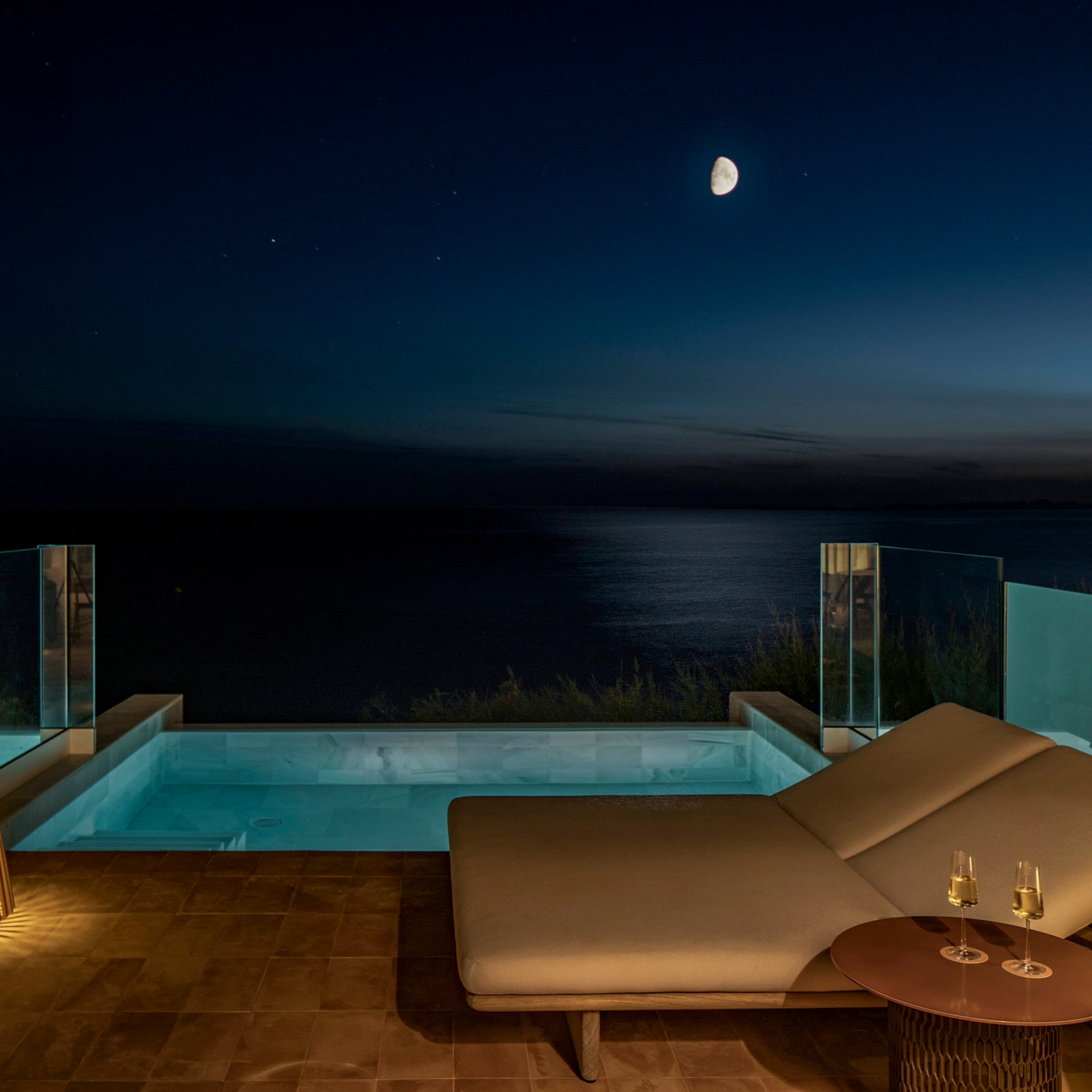 a lounge chair and a pool with a table and a lamp