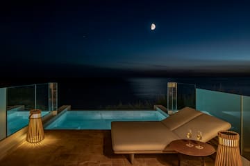 a lounge chair and a pool with a table and a lamp