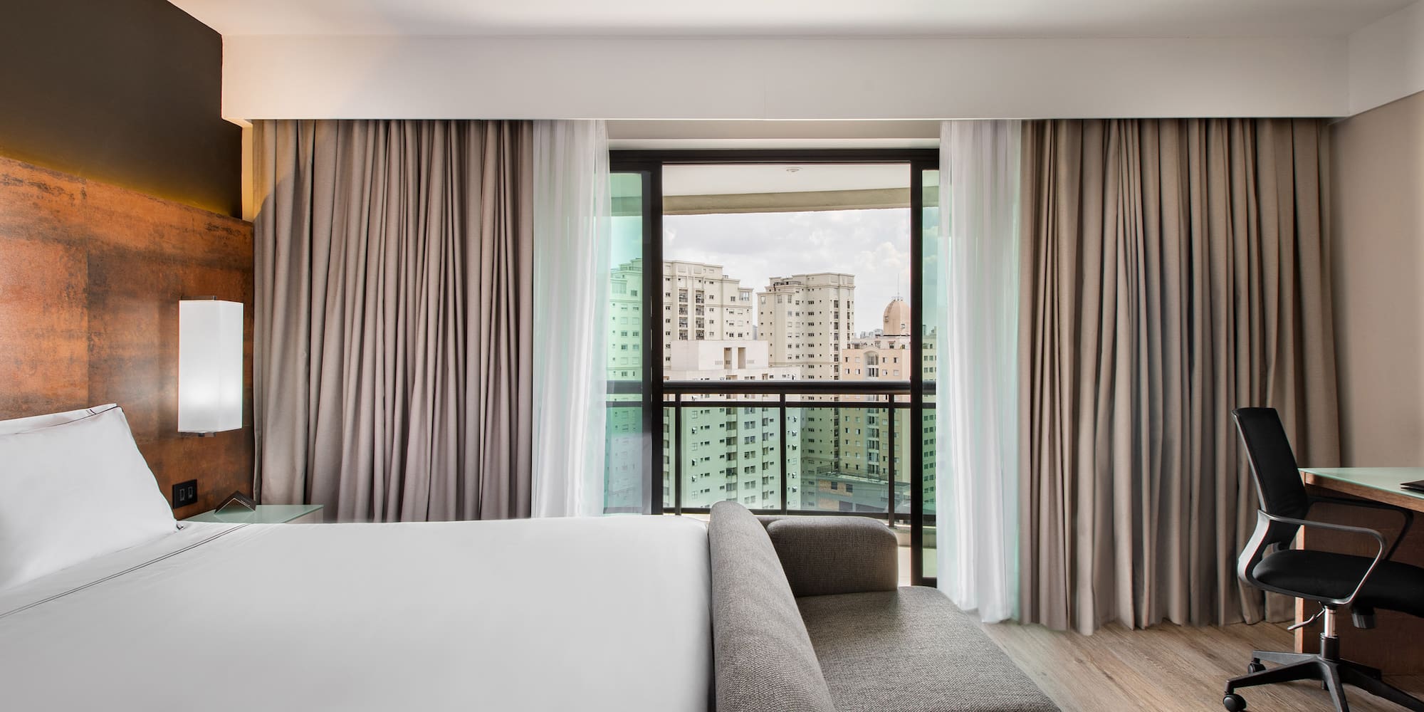 a room with a bed and couches and a window with a view of a city