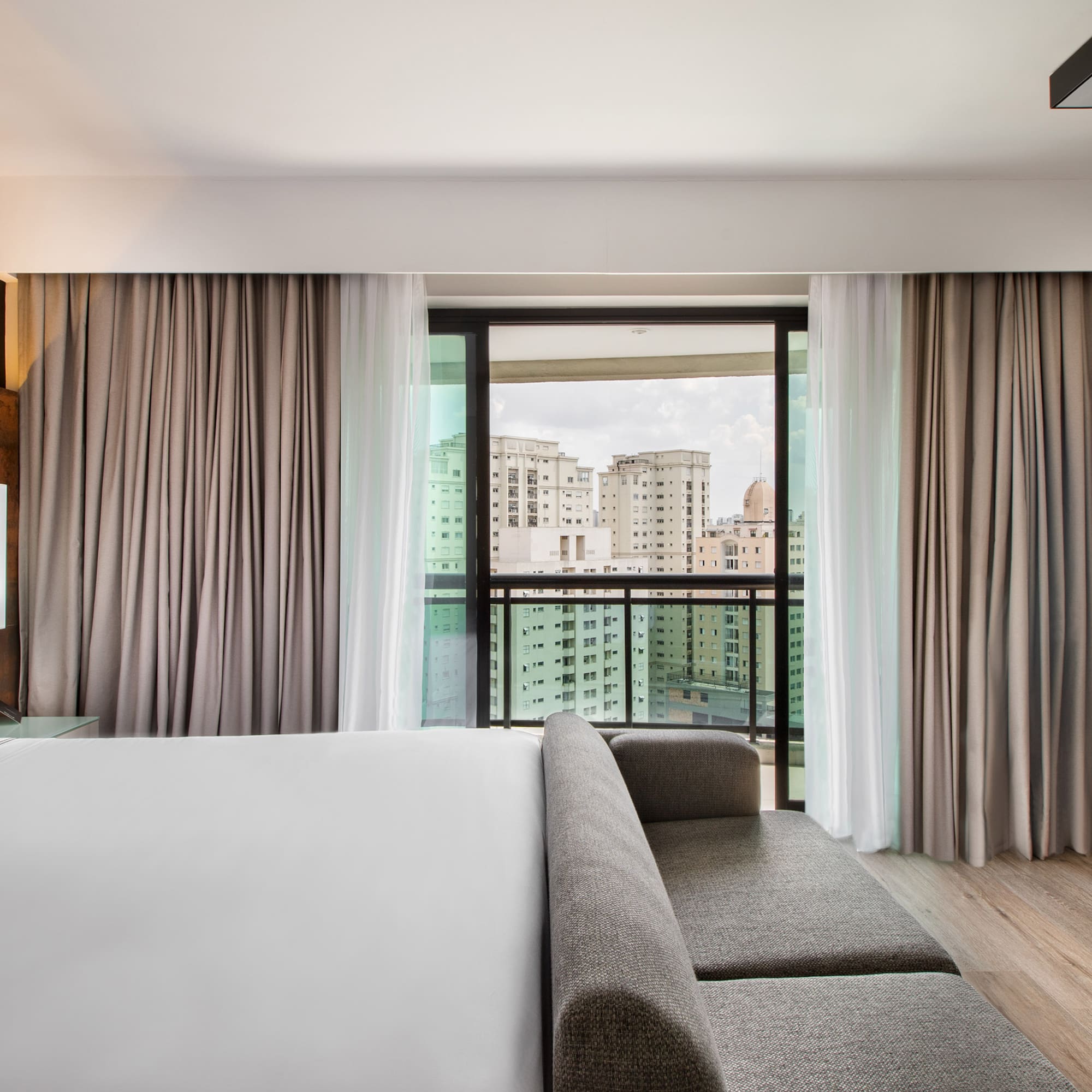 a room with a bed and couches and a window with a view of a city