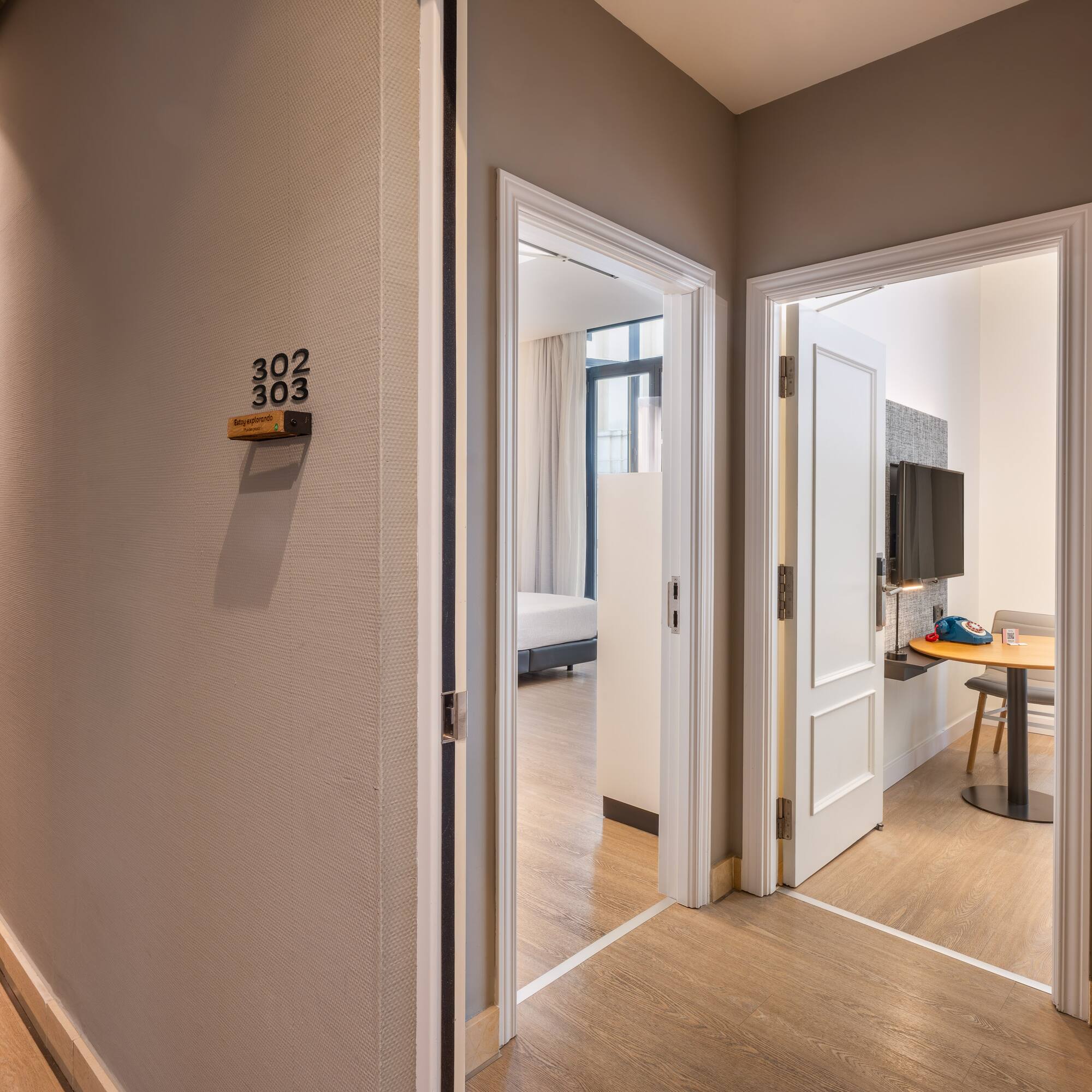 Modern hotel hallway with open doors to guest rooms 302 and 303.