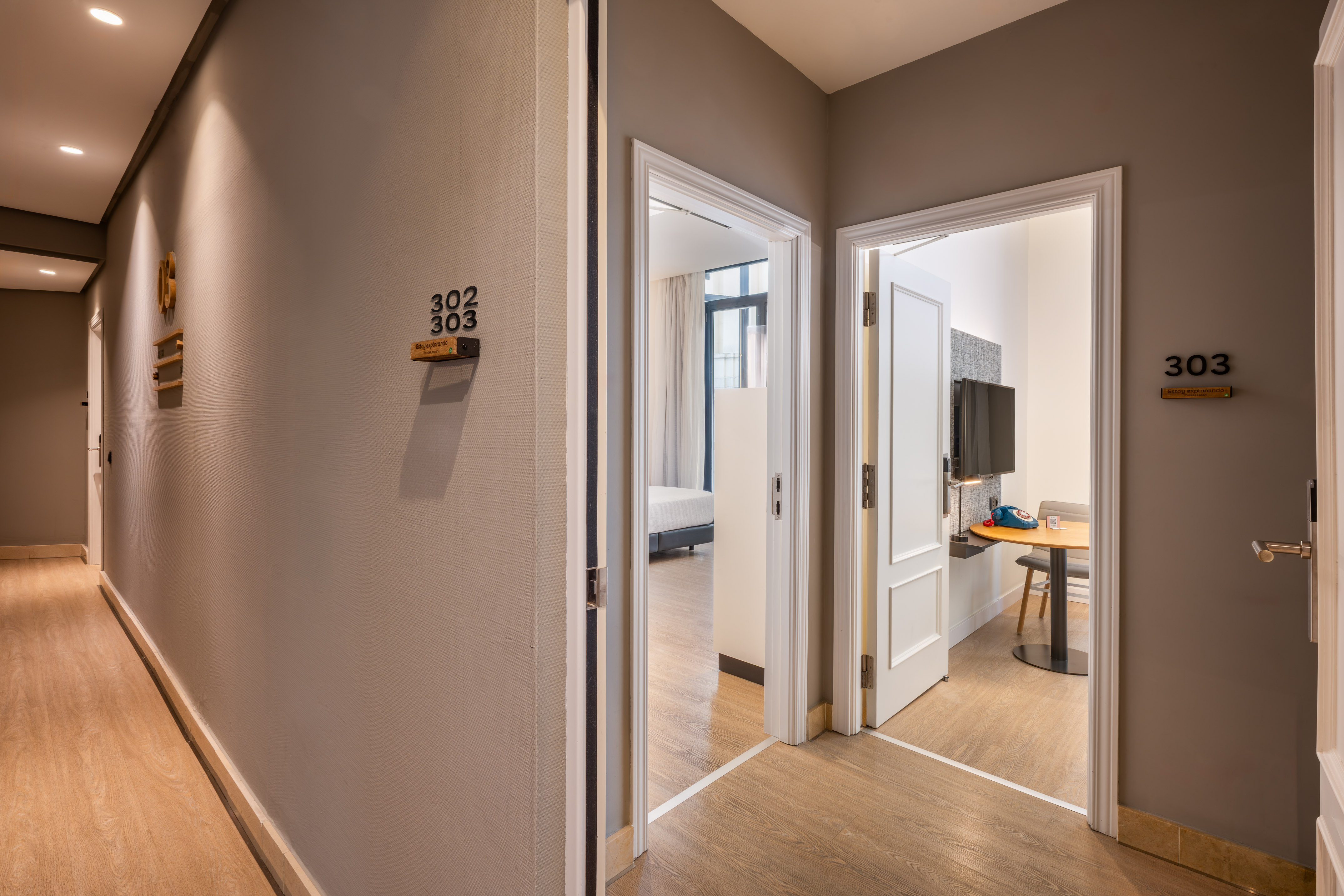 Hotel hallway, open doors to modern rooms 302 and 303.