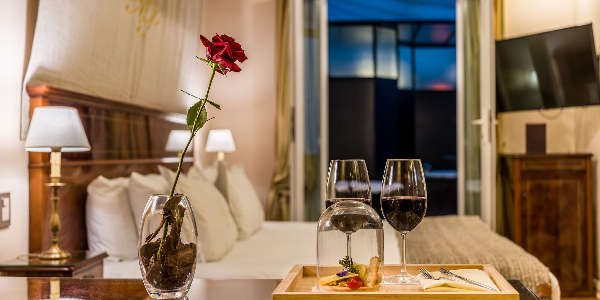 a table with wine glasses and a rose in it