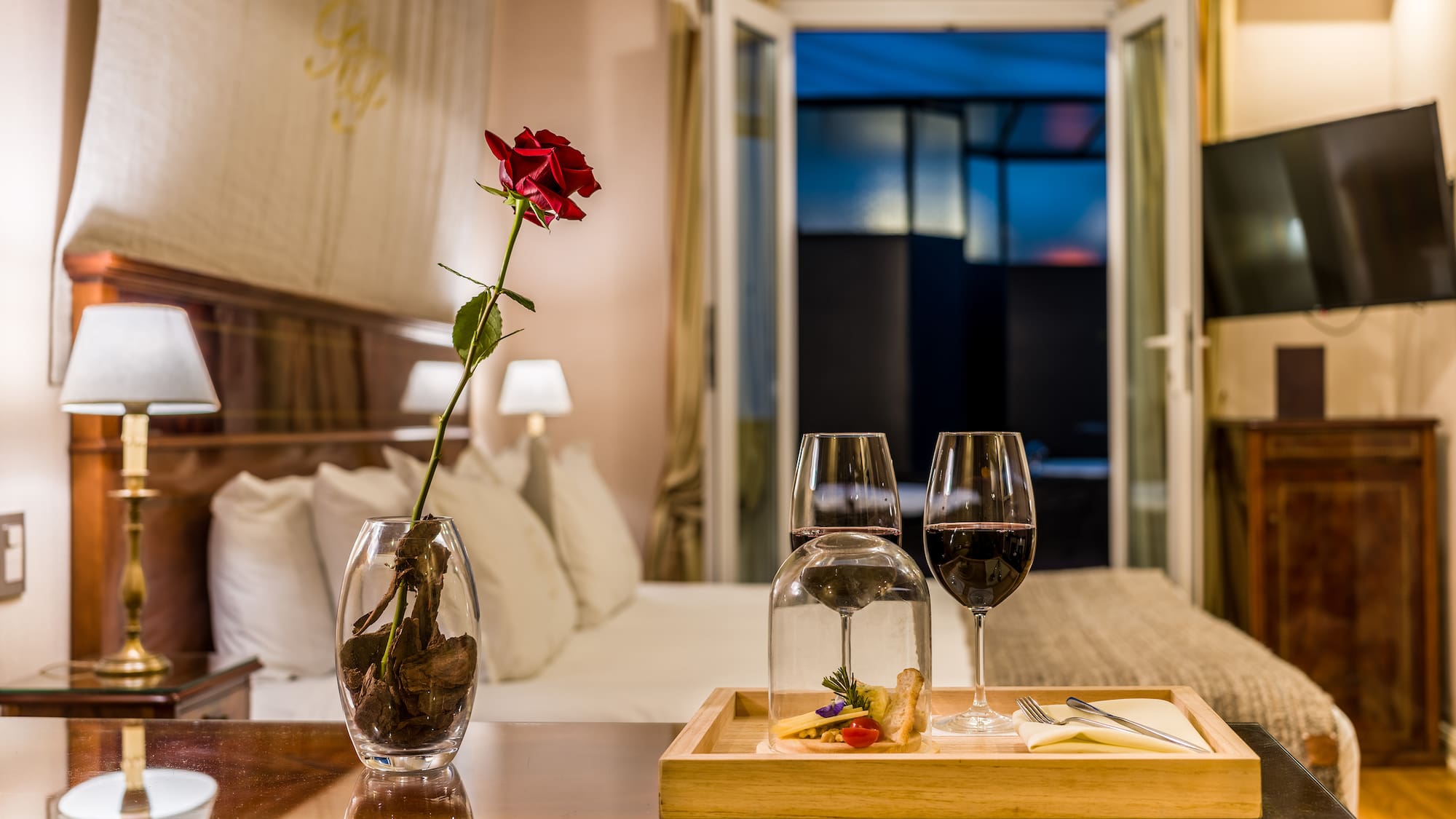 a table with wine glasses and a rose in it