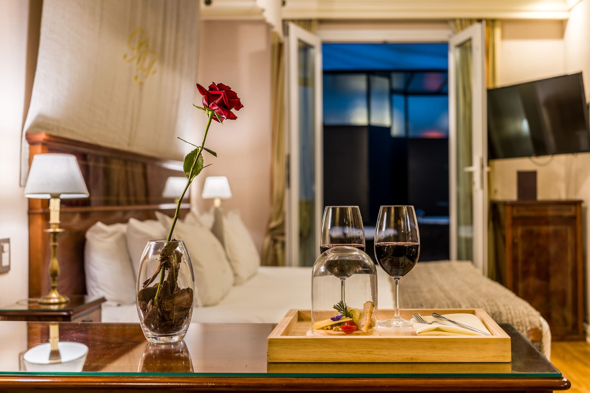 a table with wine glasses and a rose in it