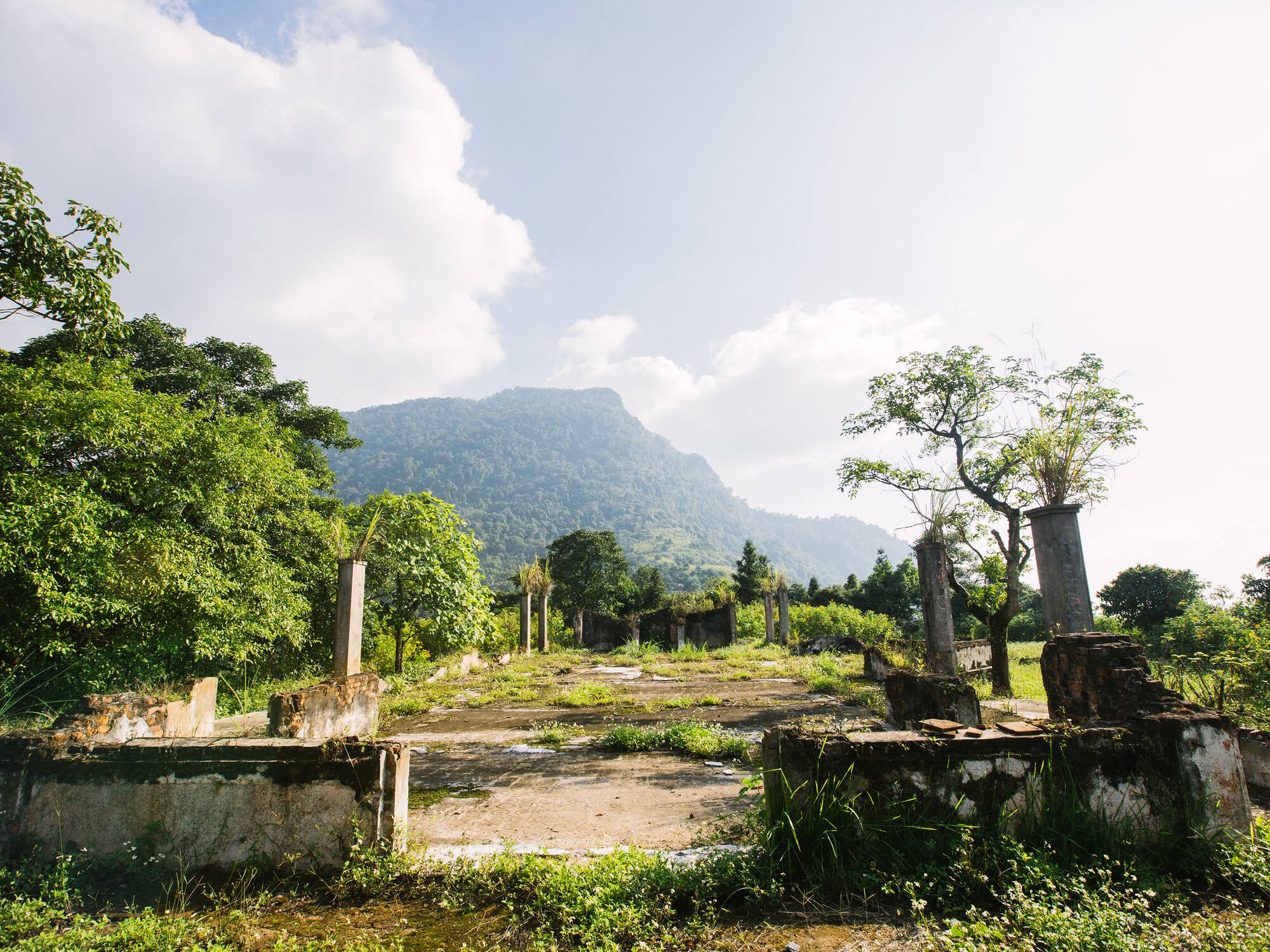 a ruins of an old building with trees and mountains in the background