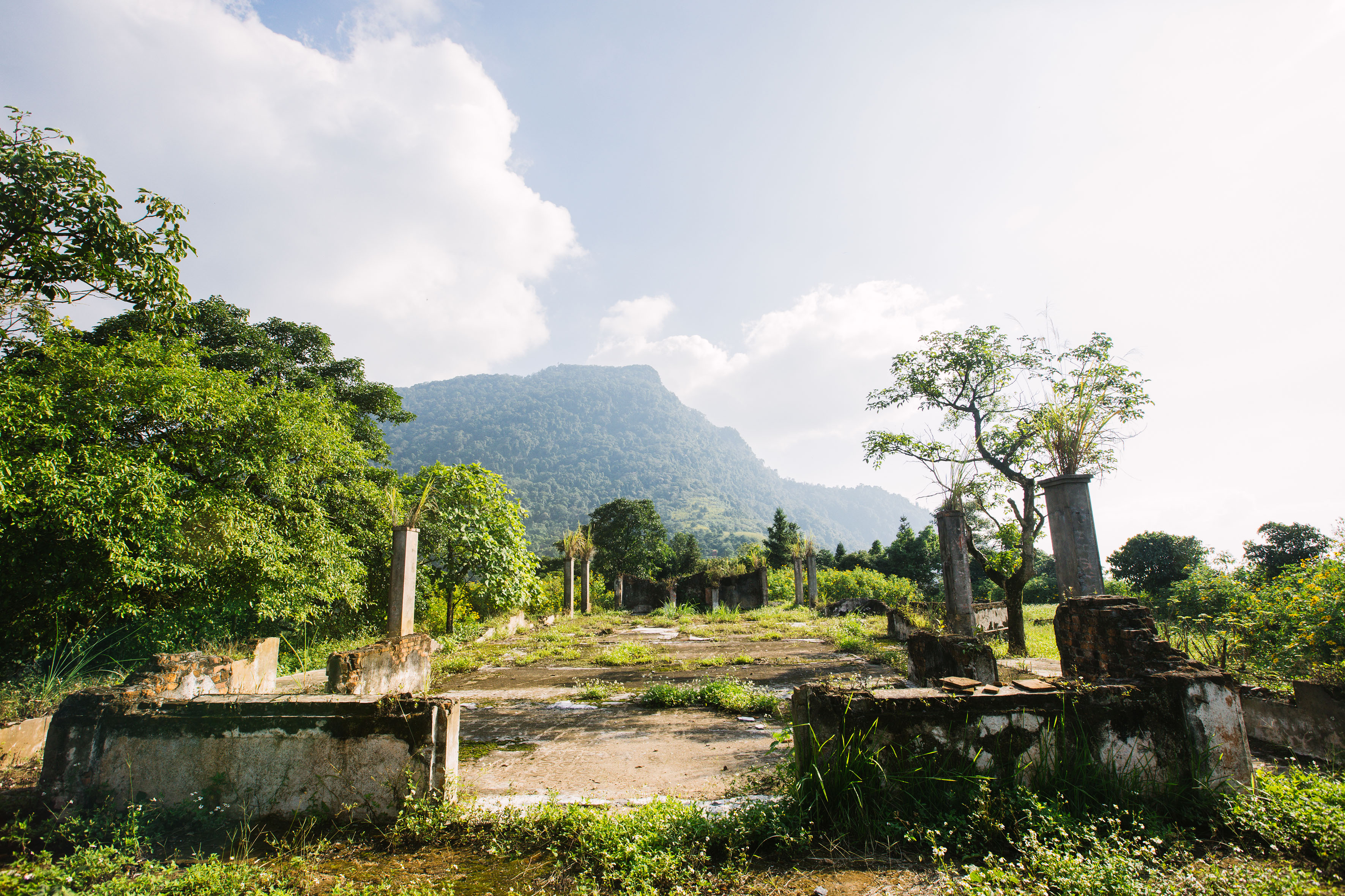 a ruins of an old building with trees and mountains in the background