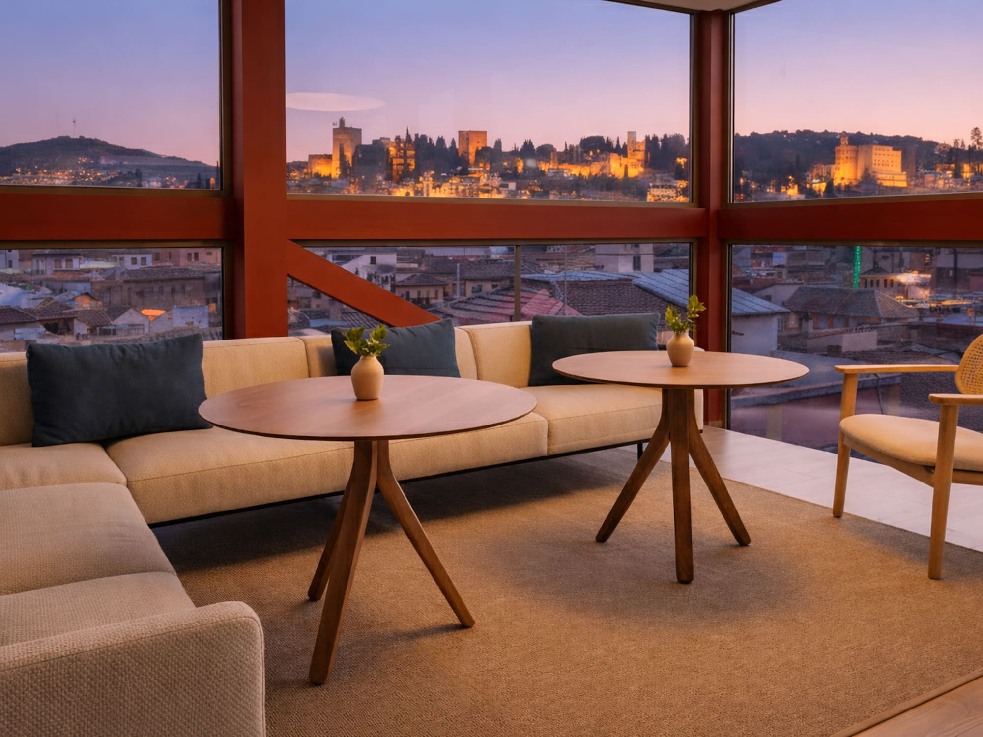 Modern lounge with panoramic views of illuminated Alhambra palace at sunset, Granada.