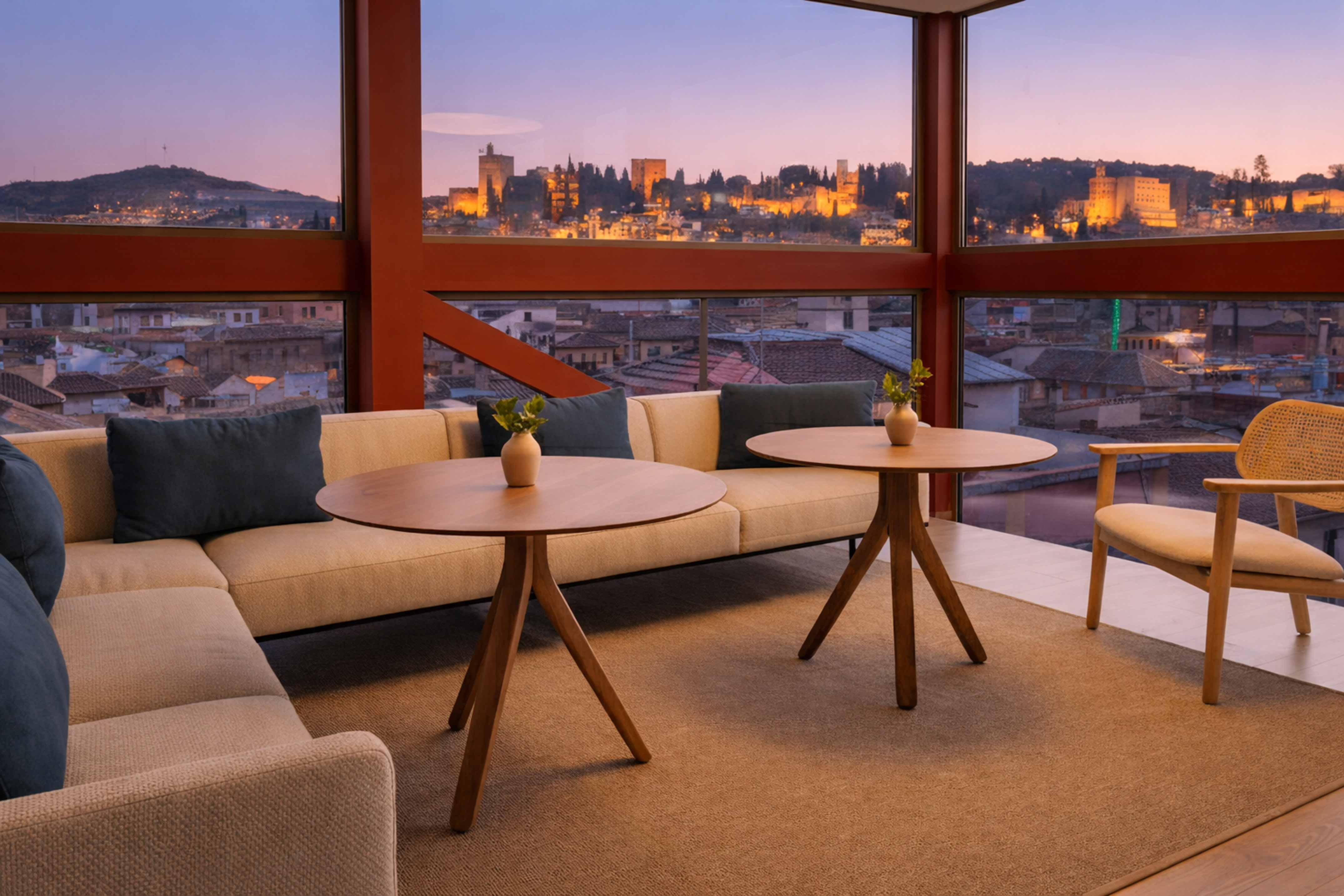 Modern lounge with panoramic views of illuminated Alhambra palace at sunset, Granada.