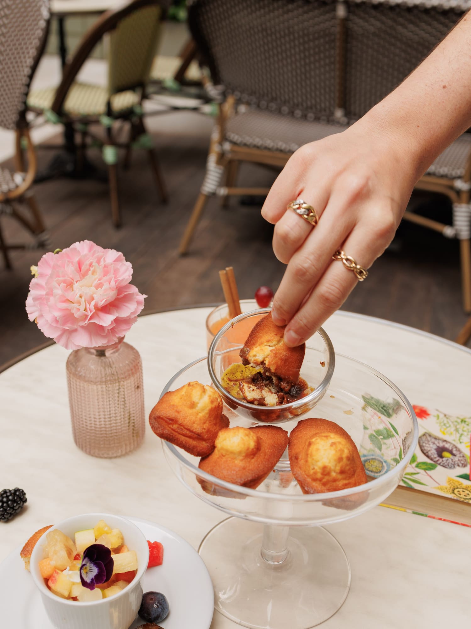 a hand holding a cupcake over a glass bowl of food
