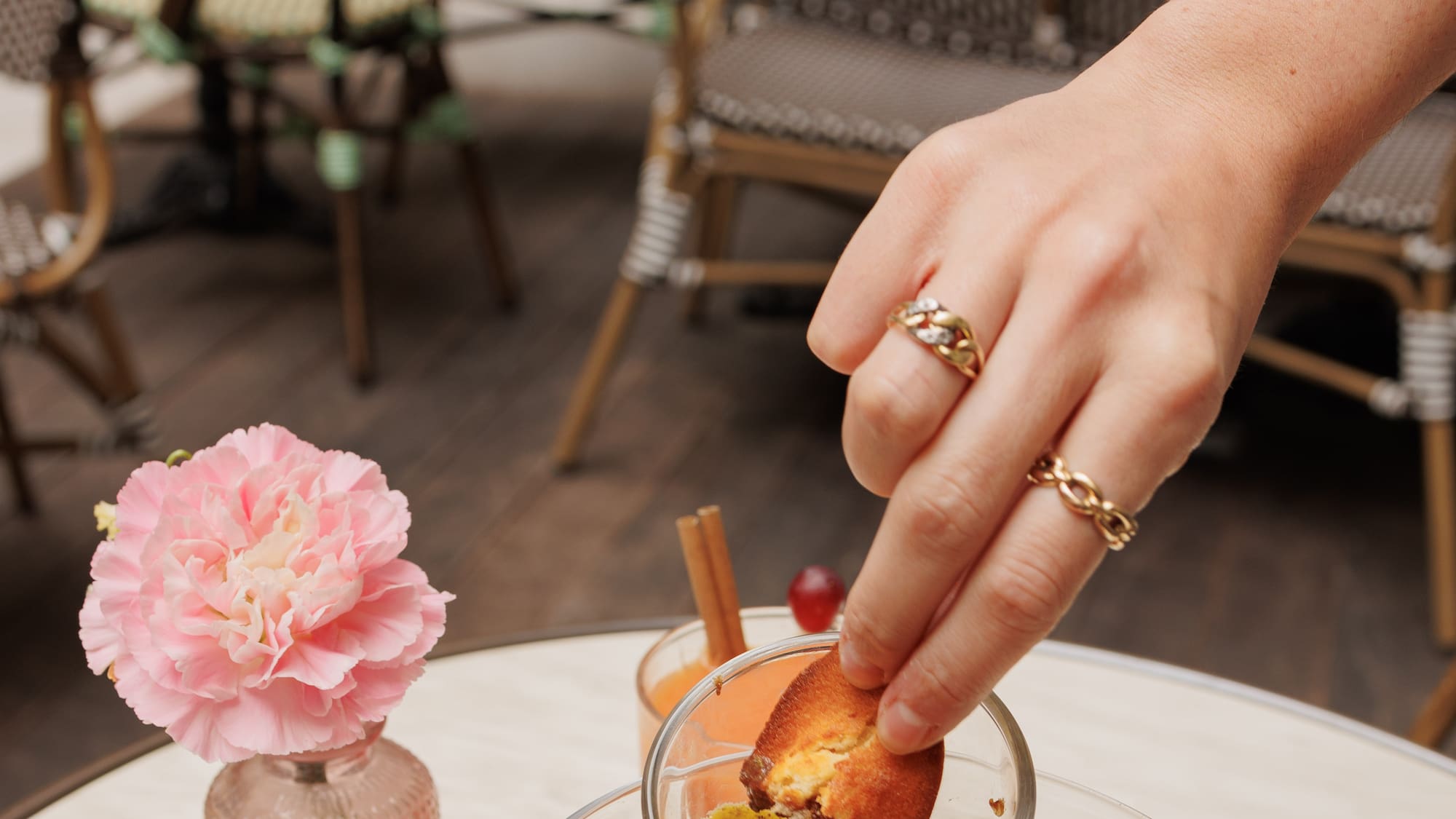 a hand holding a cupcake over a glass bowl of food