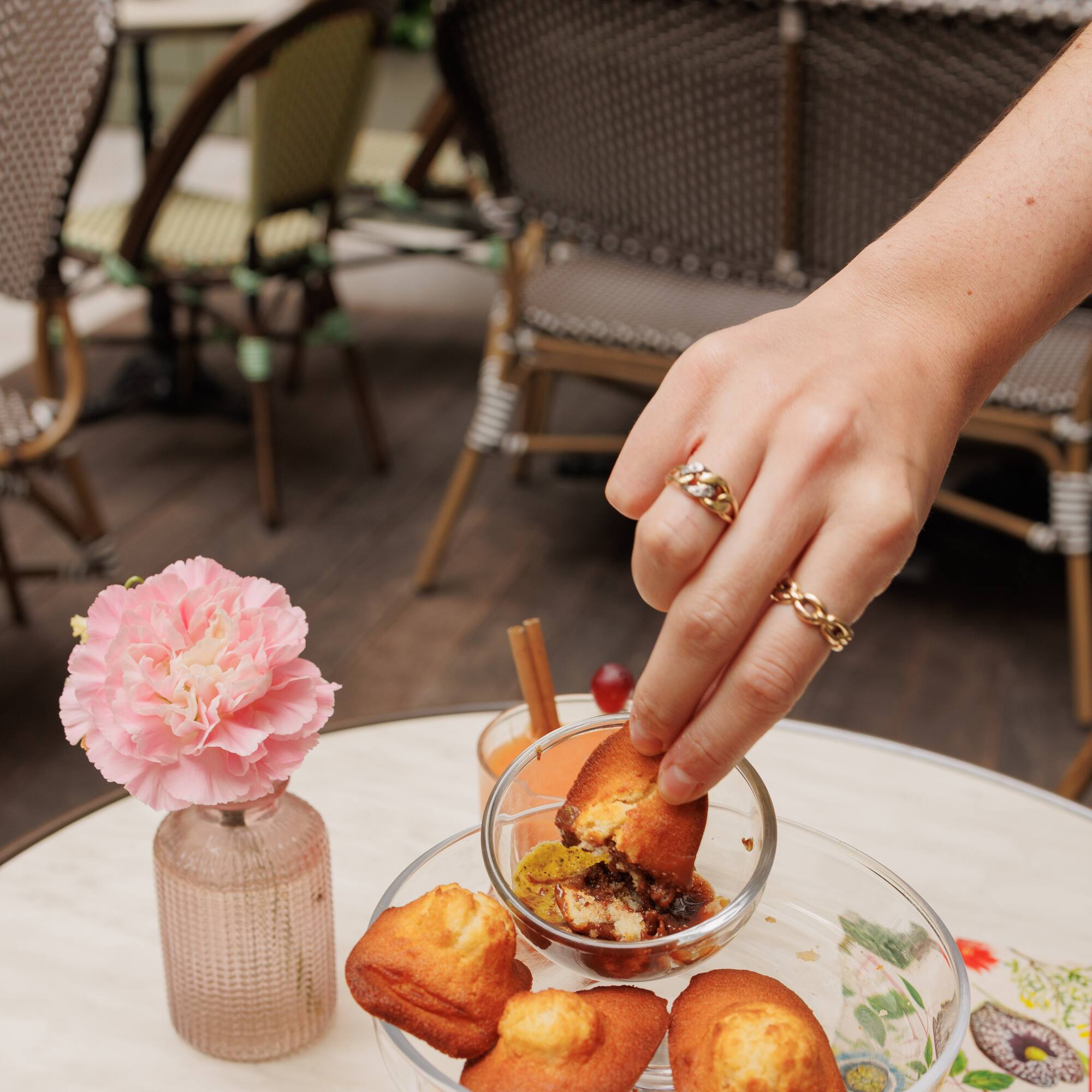 a hand holding a cupcake over a glass bowl of food