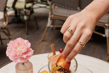 a hand holding a cupcake over a glass bowl of food