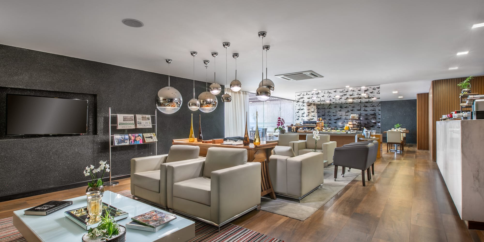Modern hotel lounge with contemporary seating, pendant lights, and buffet area.