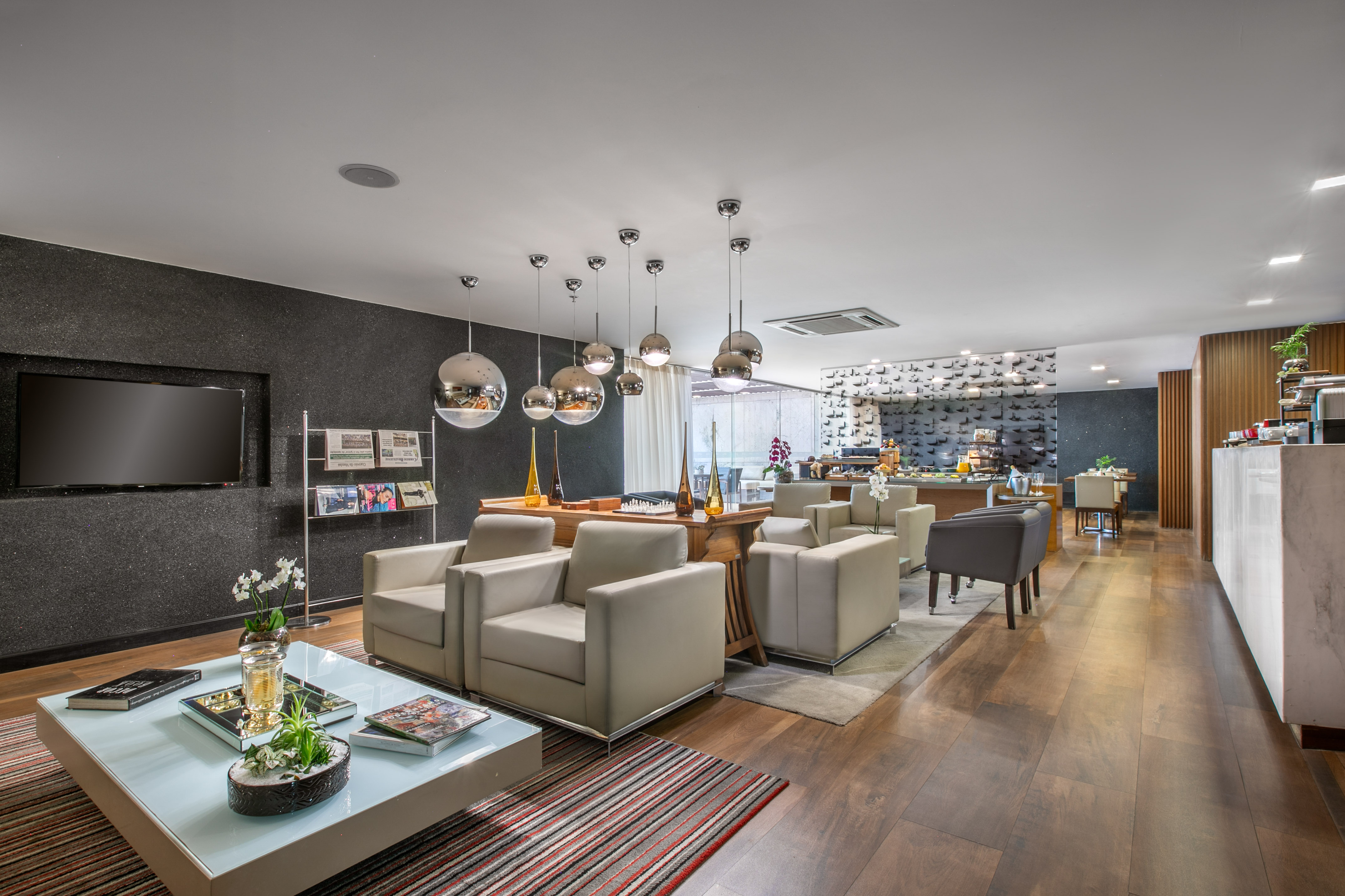 Modern hotel lounge with contemporary seating, pendant lights, and buffet area.