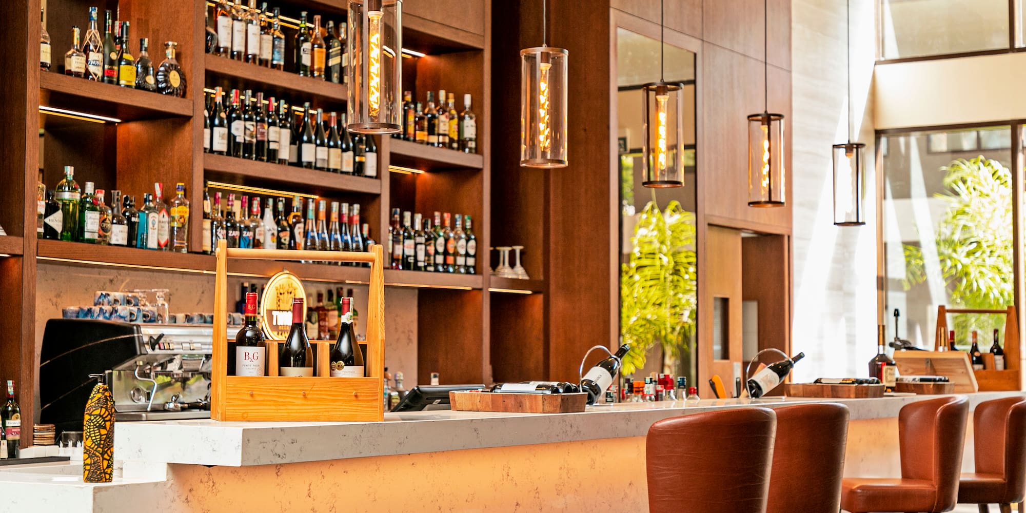 a bar with bottles of wine and chairs in front of shelves of liquor