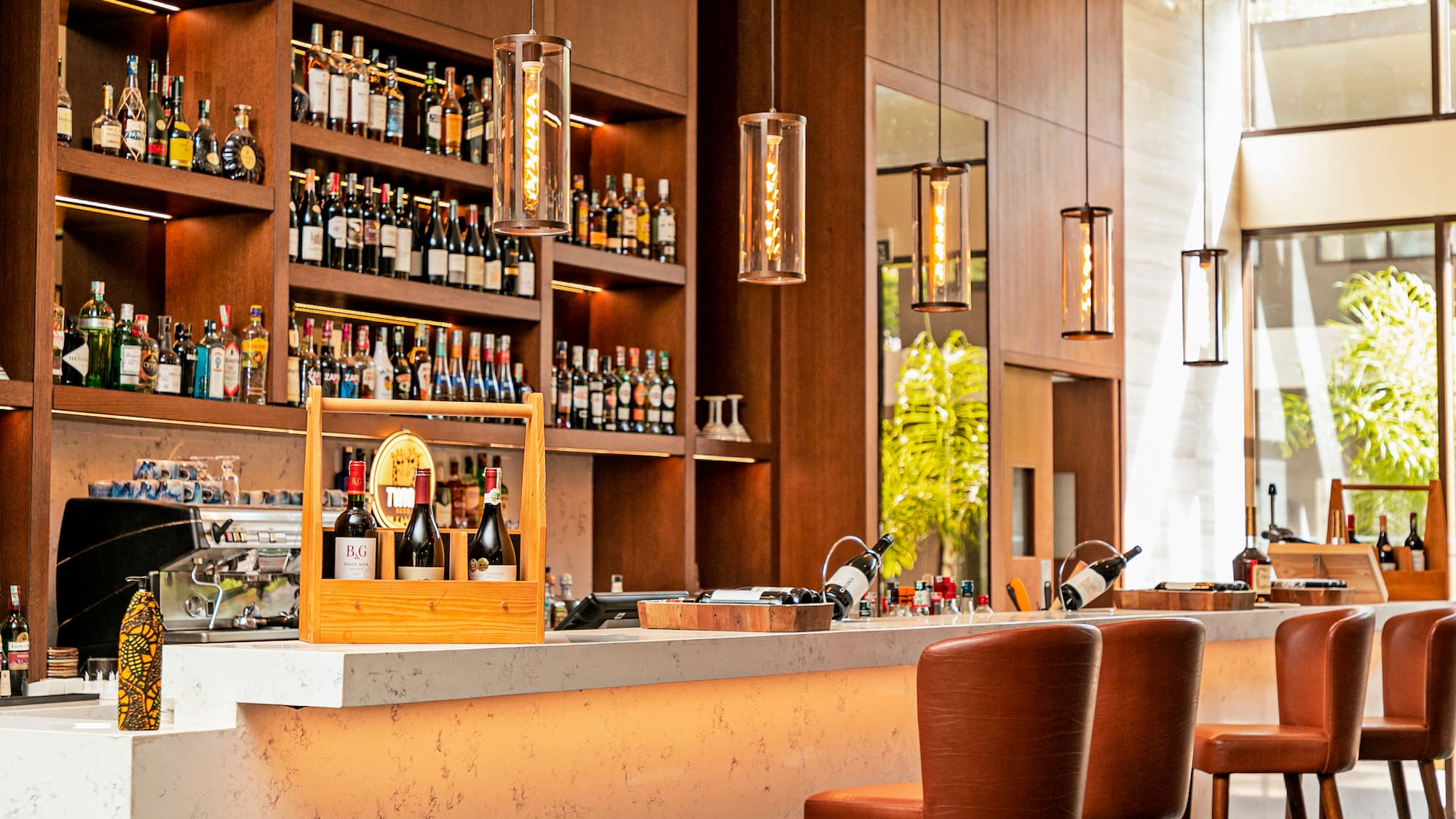a bar with bottles of wine and chairs in front of shelves of liquor