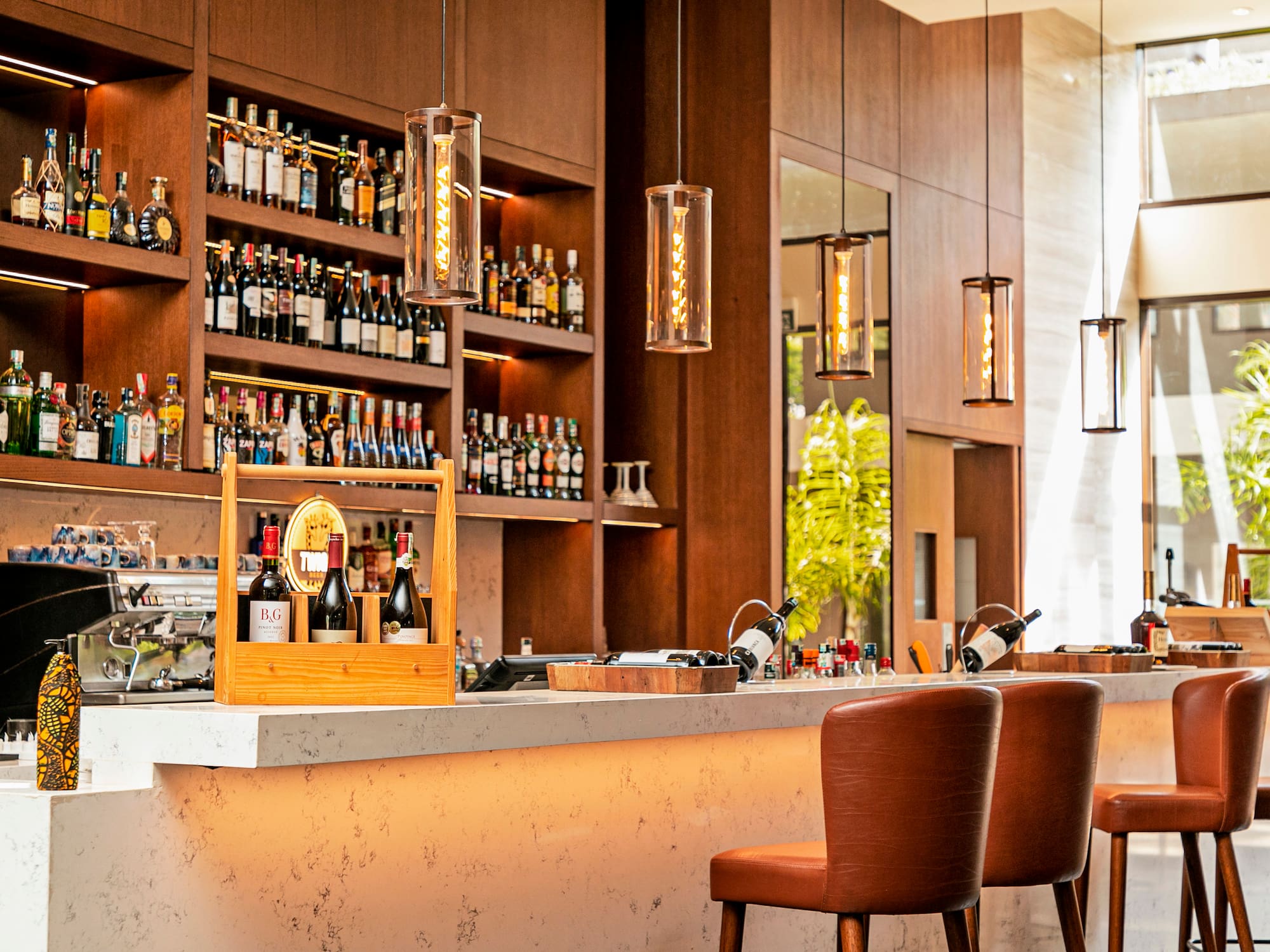 a bar with bottles of wine and chairs in front of shelves of liquor