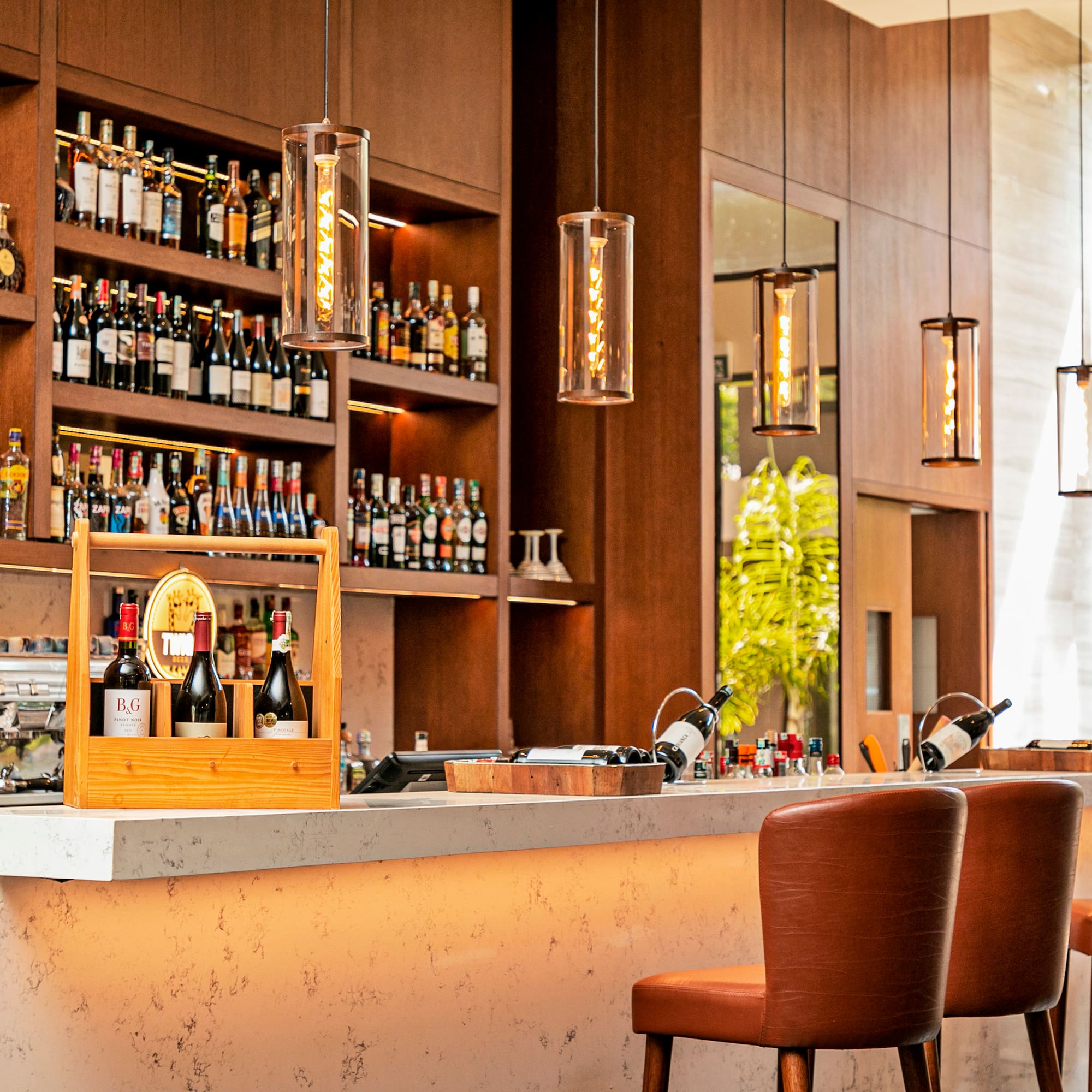 a bar with bottles of wine and chairs in front of shelves of liquor