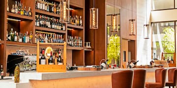 a bar with bottles of wine and chairs in front of shelves of liquor