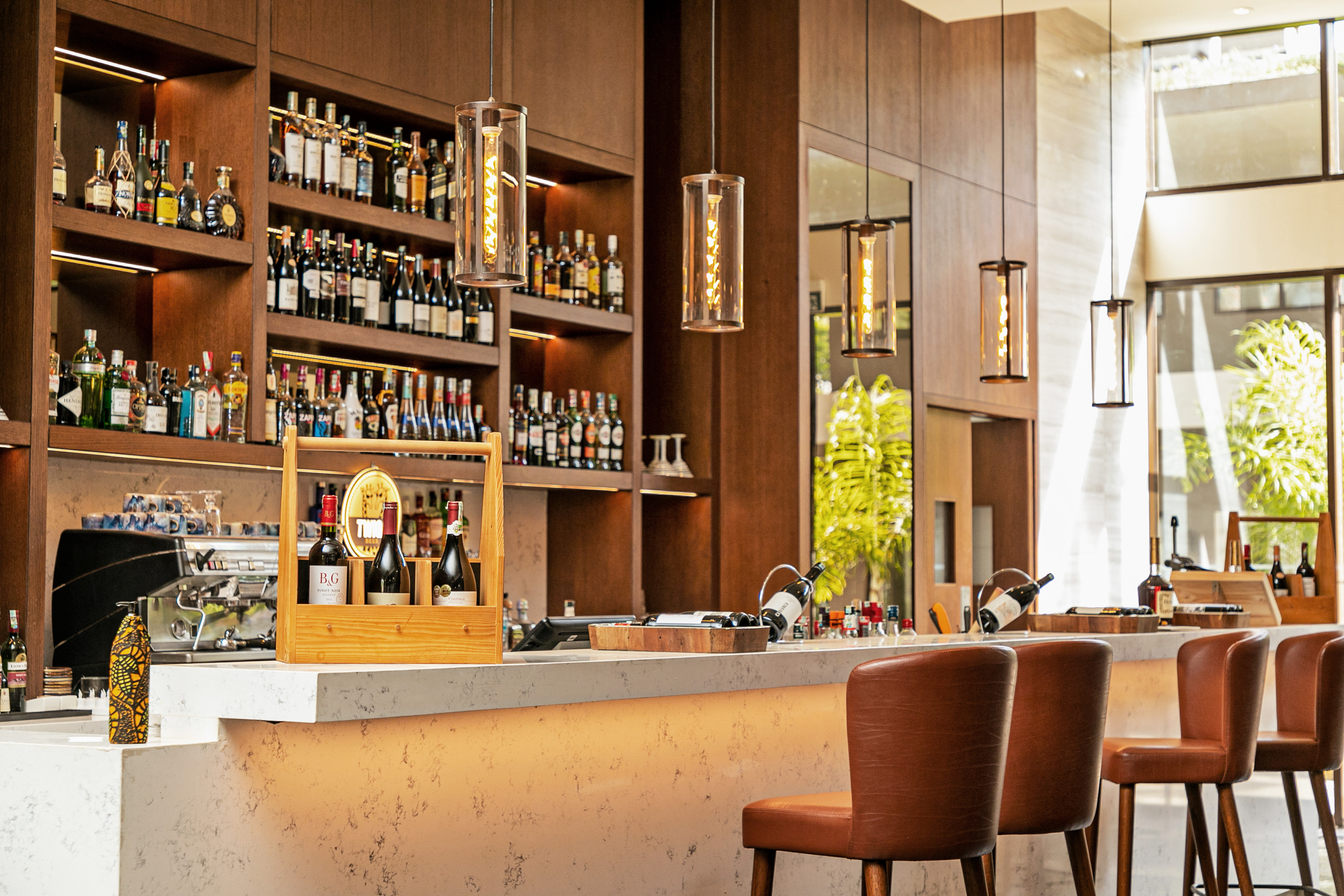 Modern bar with liquor shelves, wine, sleek counter, and leather bar stools.