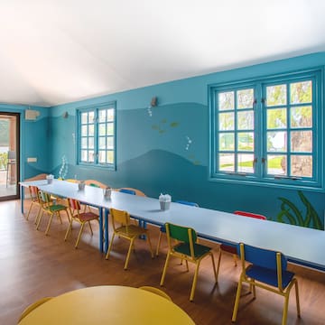 a room with a long table and colorful chairs