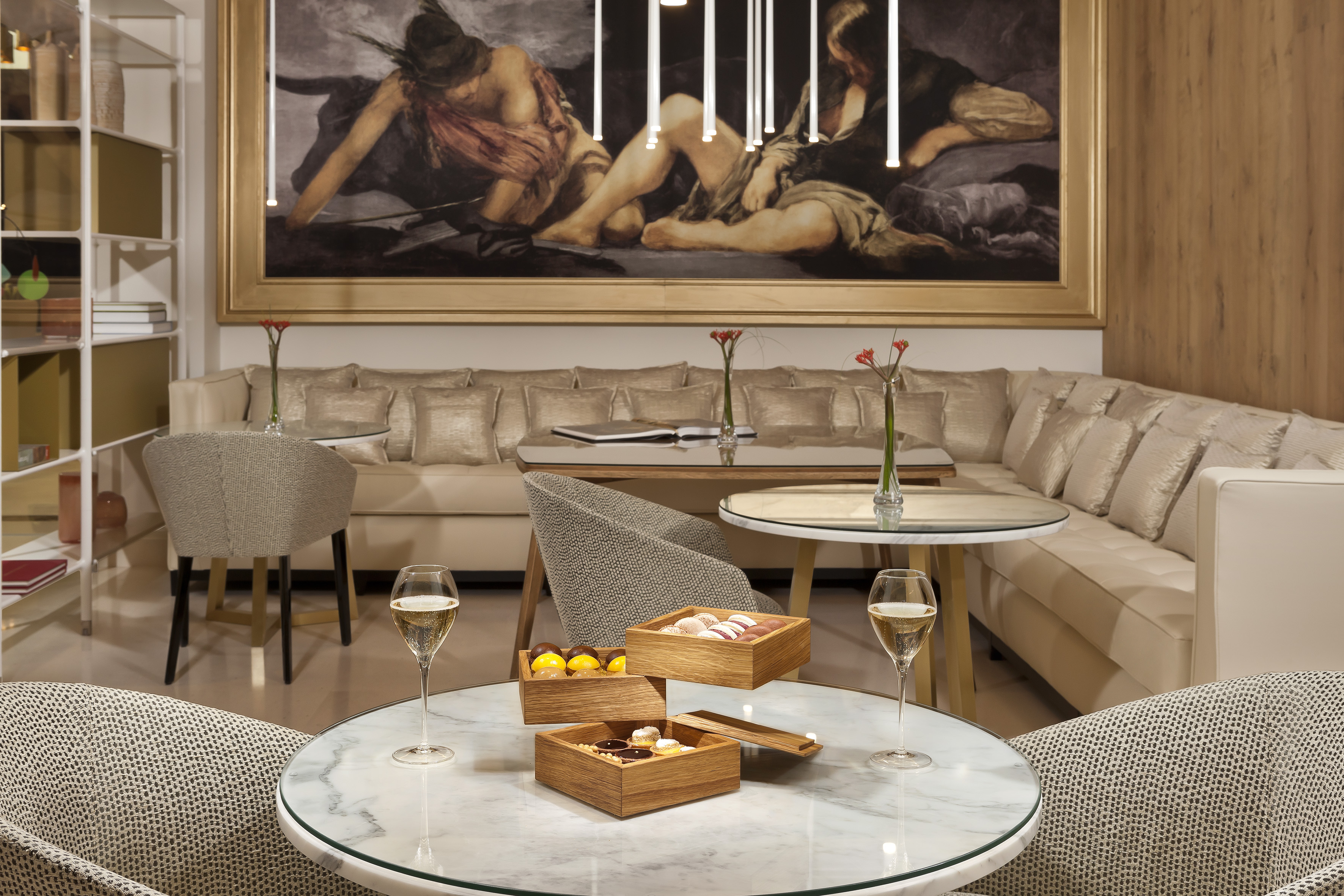 Luxurious hotel lounge with champagne, pastries, and classical artwork.
