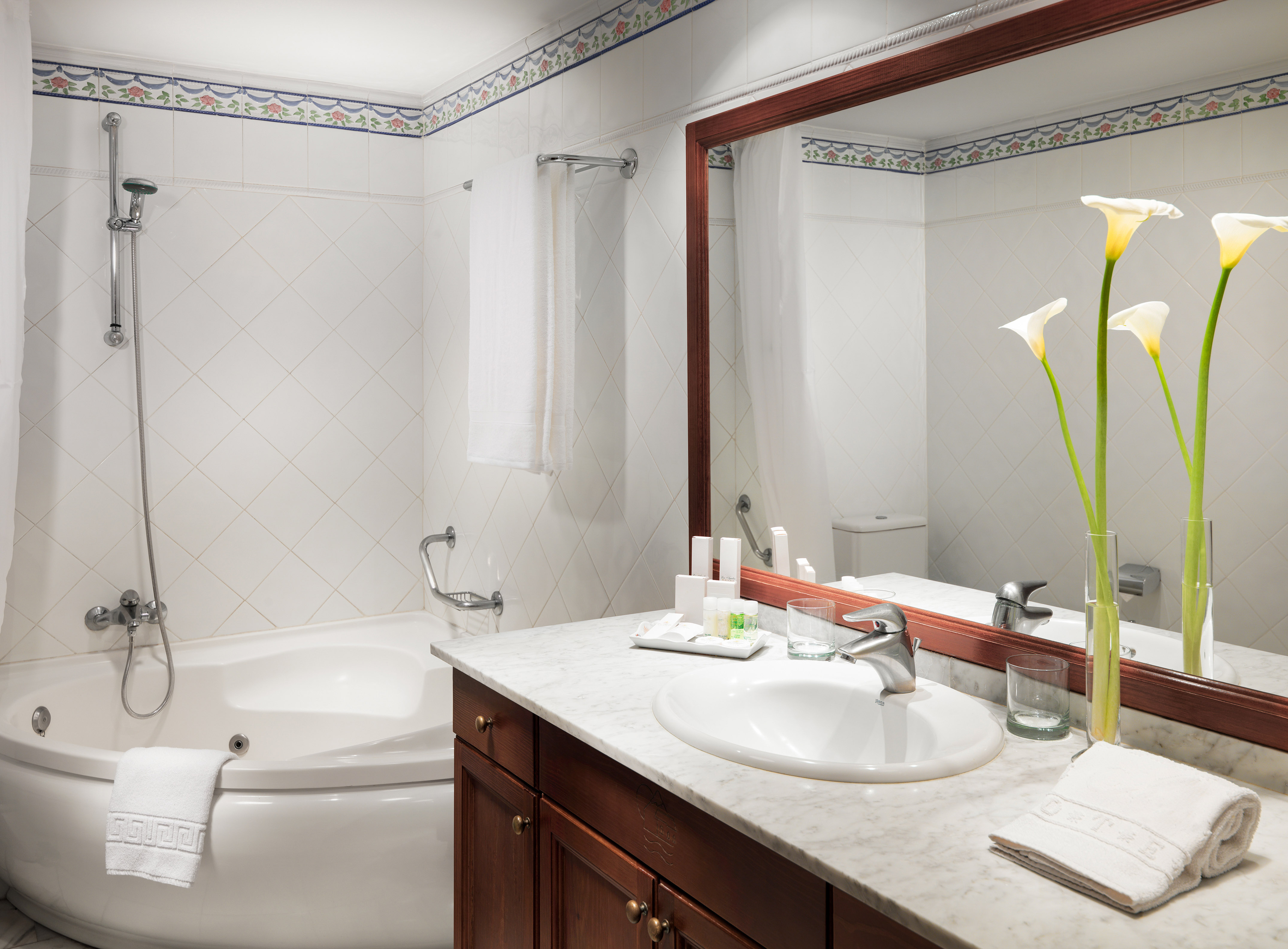 Hotel bathroom with jacuzzi tub, marble vanity, sink, and large mirror.