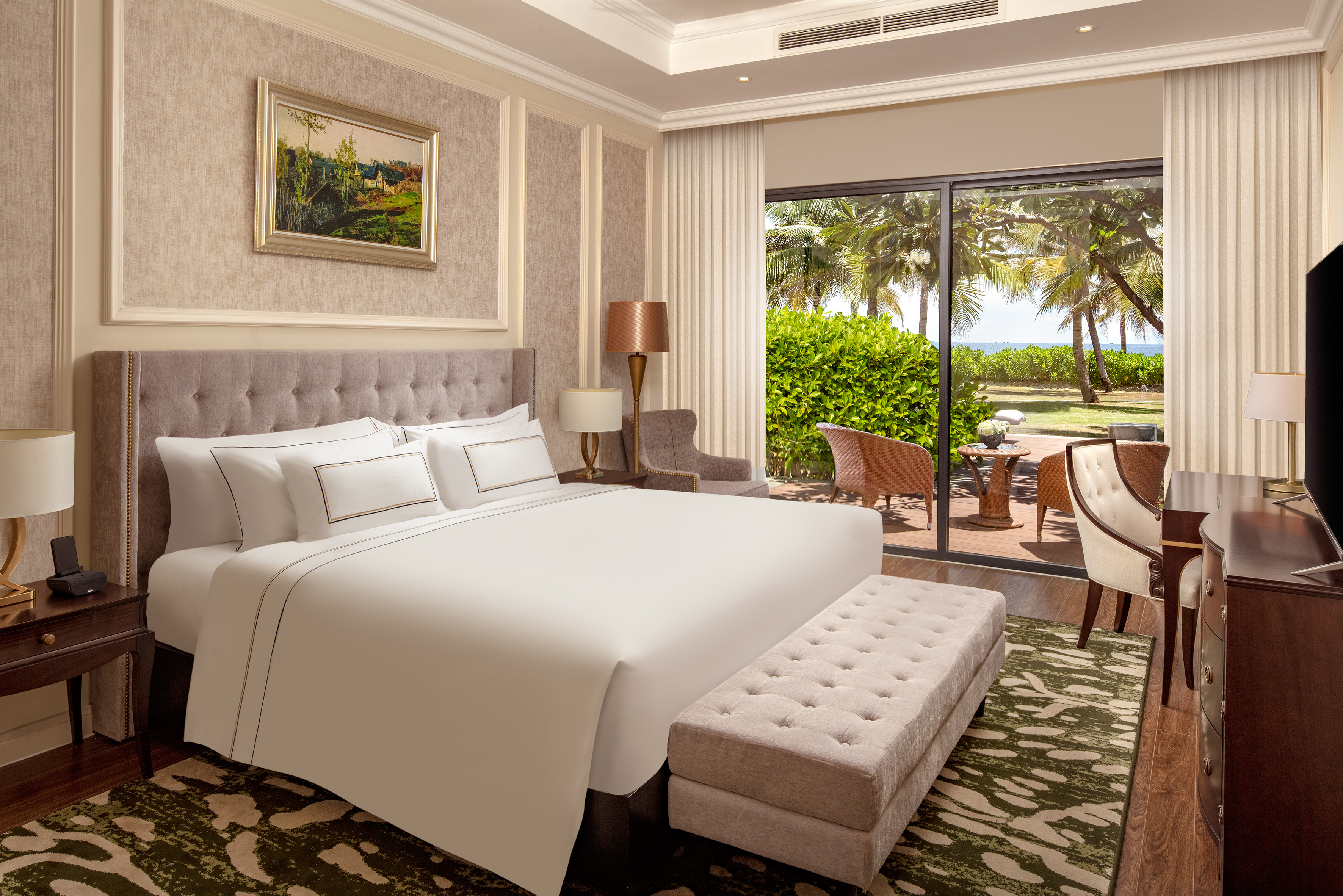 Spacious hotel bedroom with king bed, oceanfront patio, and tropical views.