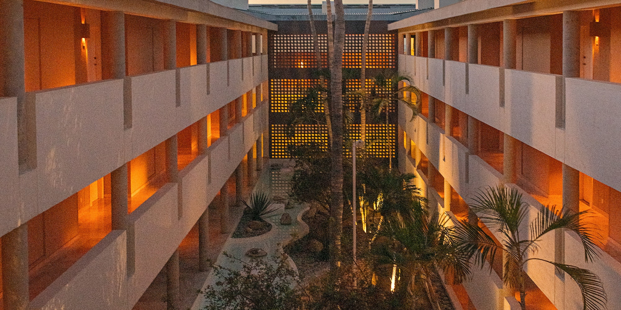 Modern hotel courtyard at dusk, illuminated rooms, palm trees, crescent moon. - Paradisus Los Cabos - Adults Only, Los Cabos