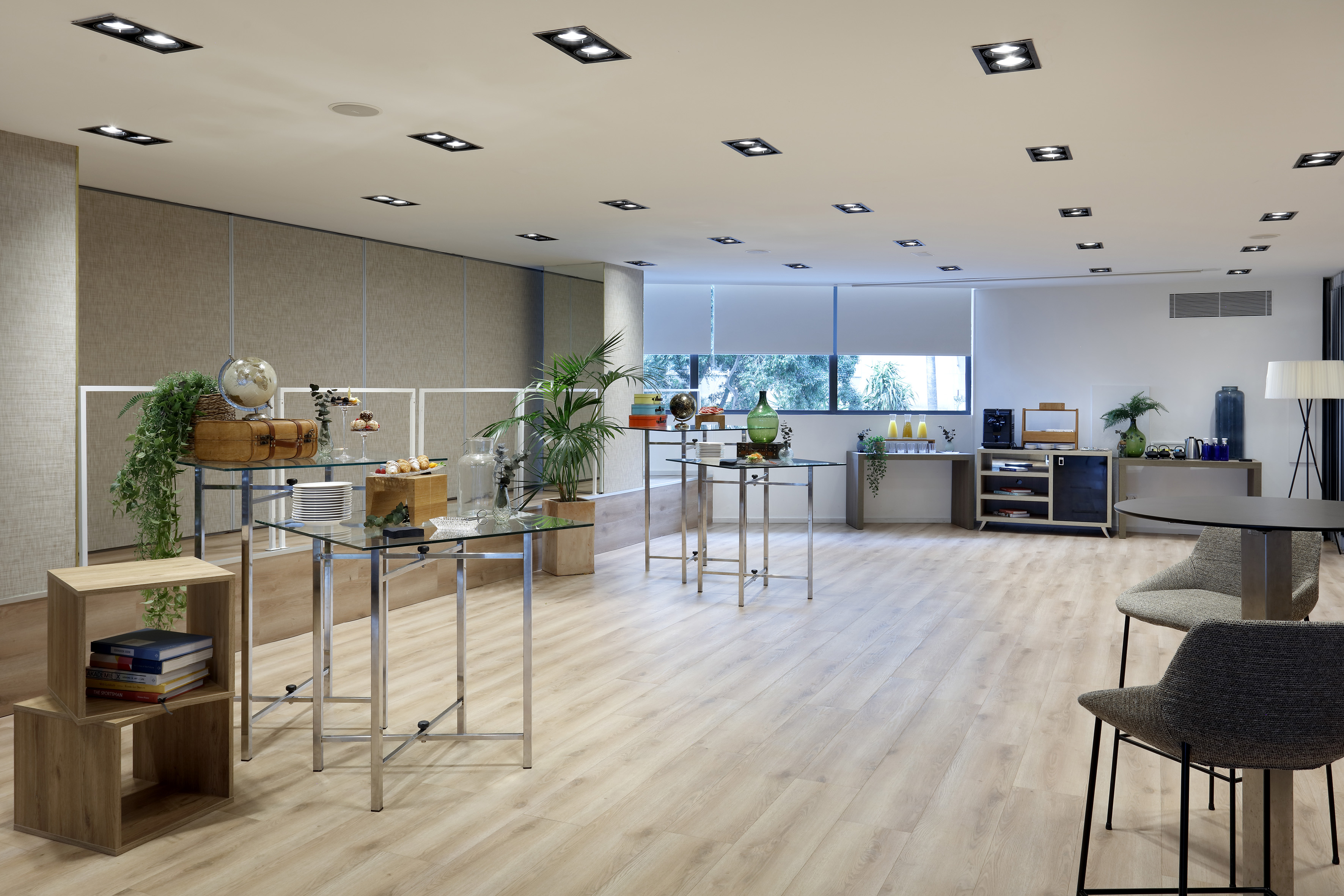 Modern event lounge with buffet tables, refreshments, and light wood floor.