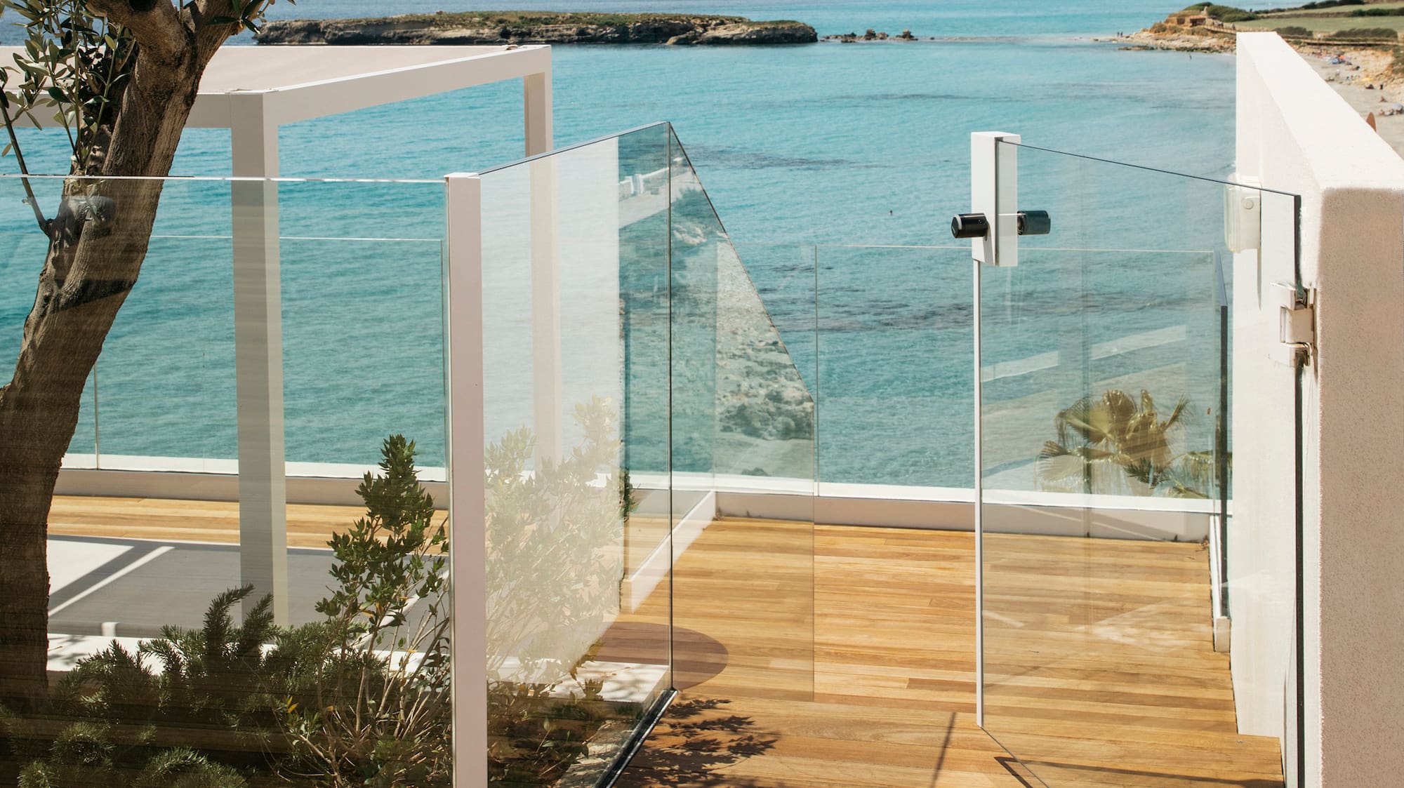 a glass fenced deck overlooking a body of water