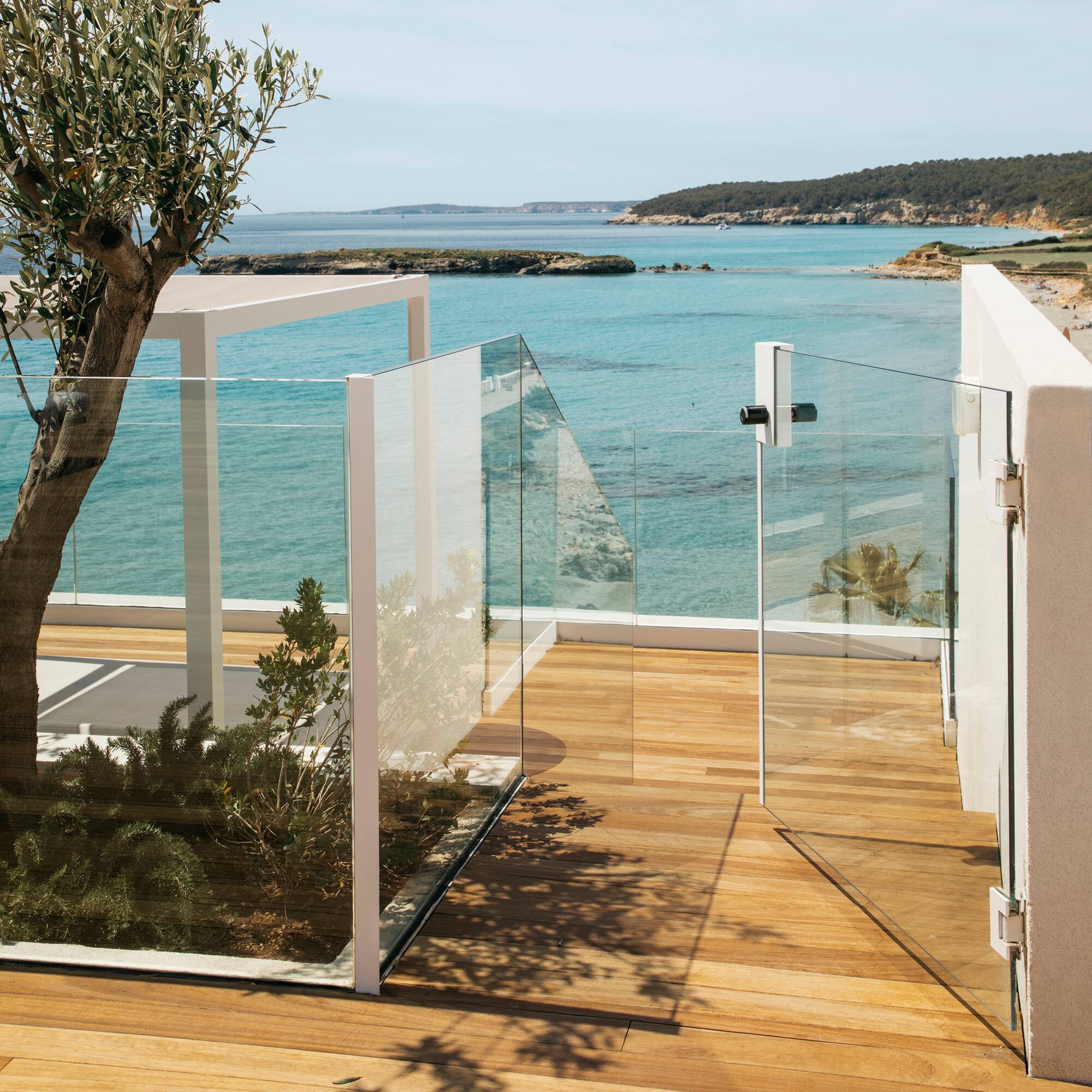 a glass fenced deck overlooking a body of water