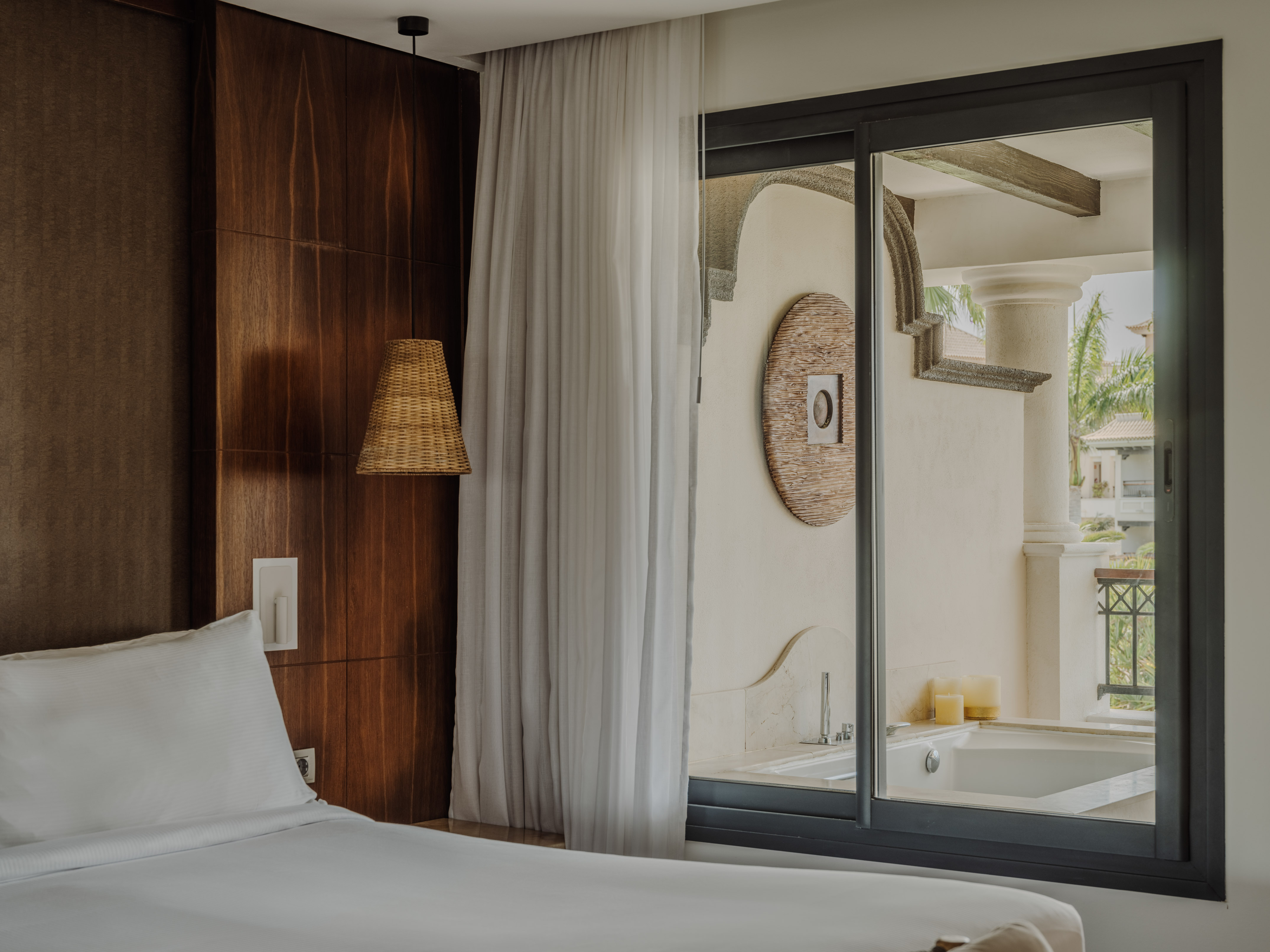 Luxury hotel bedroom with wood paneling and private outdoor spa bath.